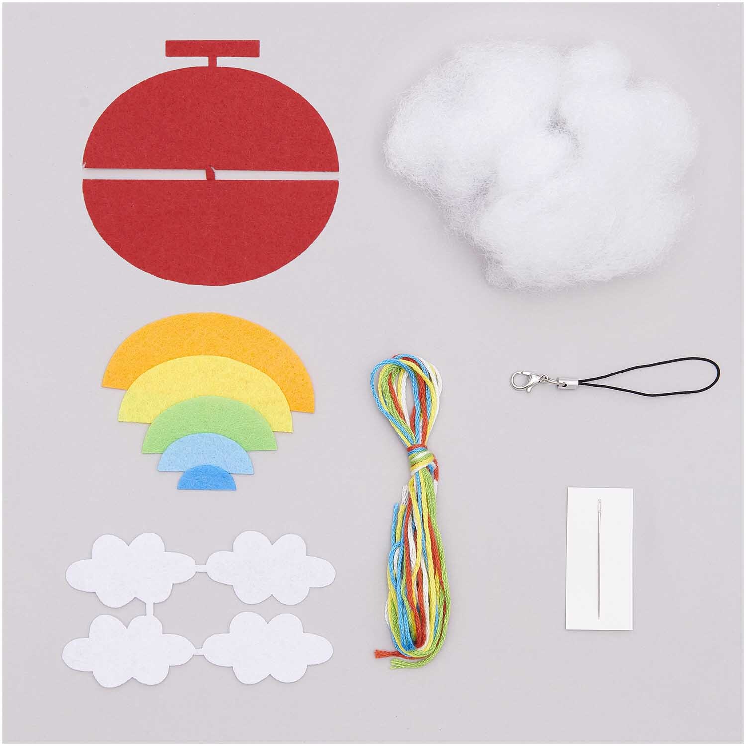 Bastelset Filz Regenbogen-Anhänger von Rico Design mit bunten Filzteilen, Füllmaterial und Zubehör auf grauem Hintergrund. Ideal für kreative Projekte.