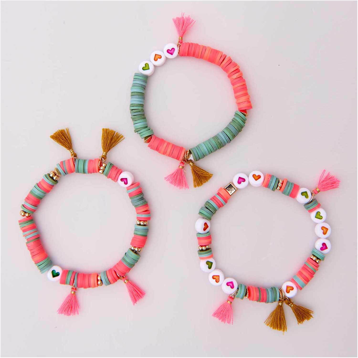 Mix it Up - Jewellery Mini-Quaste 11mm: Drei bunte Armbänder mit Quasten und Herzperlen in Gold-Senf und Rosa von Rico Design.