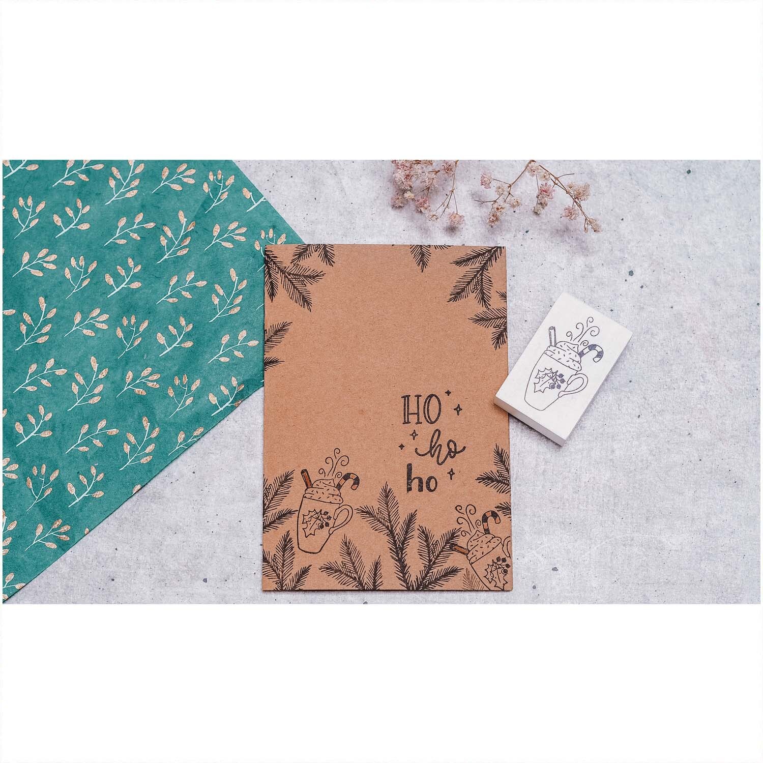 Stempel Weihnachtsbecher weiß 35x55mm von May&Berry neben einer Karte mit weihnachtlichem Design auf grauem Hintergrund.