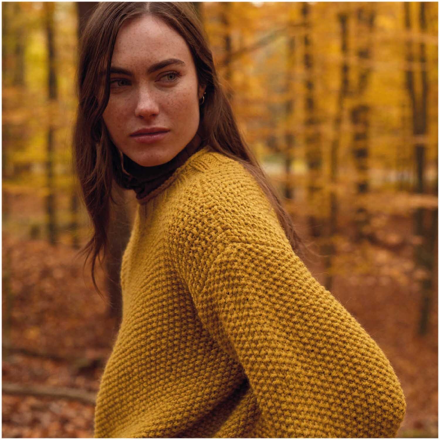 Essentials Alpaca Twist Chunky: Frau in senfgelbem Strickpullover im herbstlichen Wald, Rico Design.