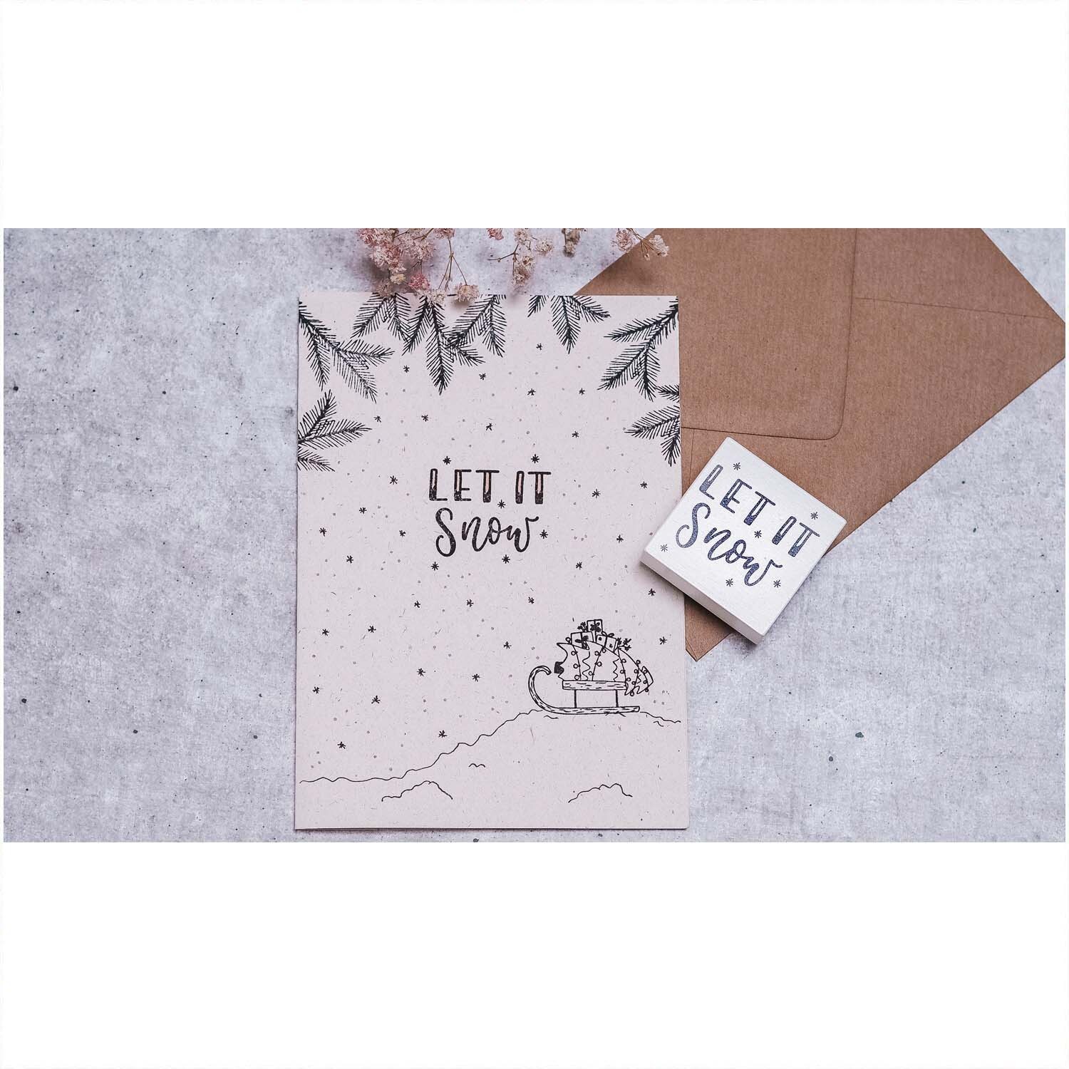 Stempel Let it snow weiß 45x45mm zeigt winterliches Design mit Schlittenmotiv und Schneeflocken. Perfekt für kreative Projekte.