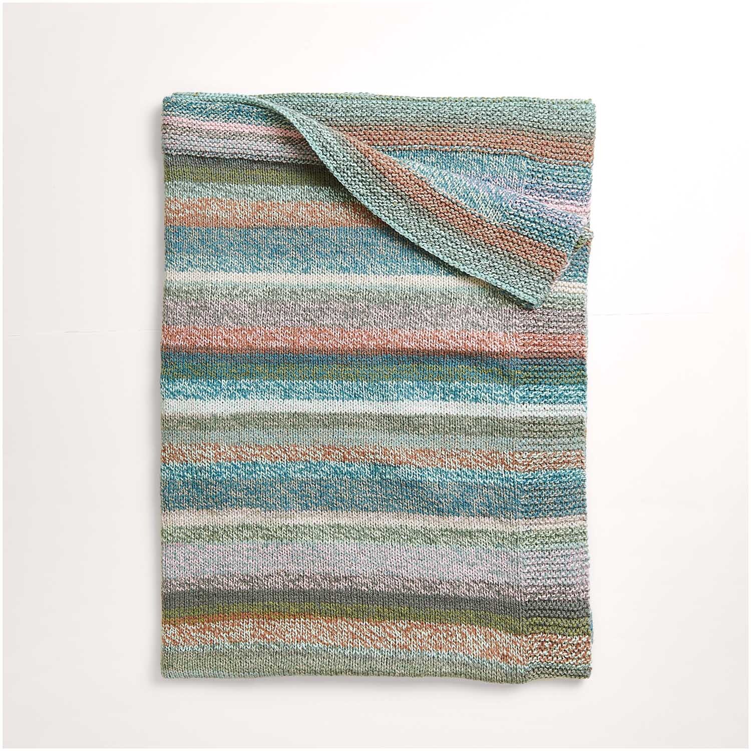 Strickset Decke Modell 05 zeigt eine gestreifte Decke in sanften Pastelltönen, ideal für gemütliche Abende.