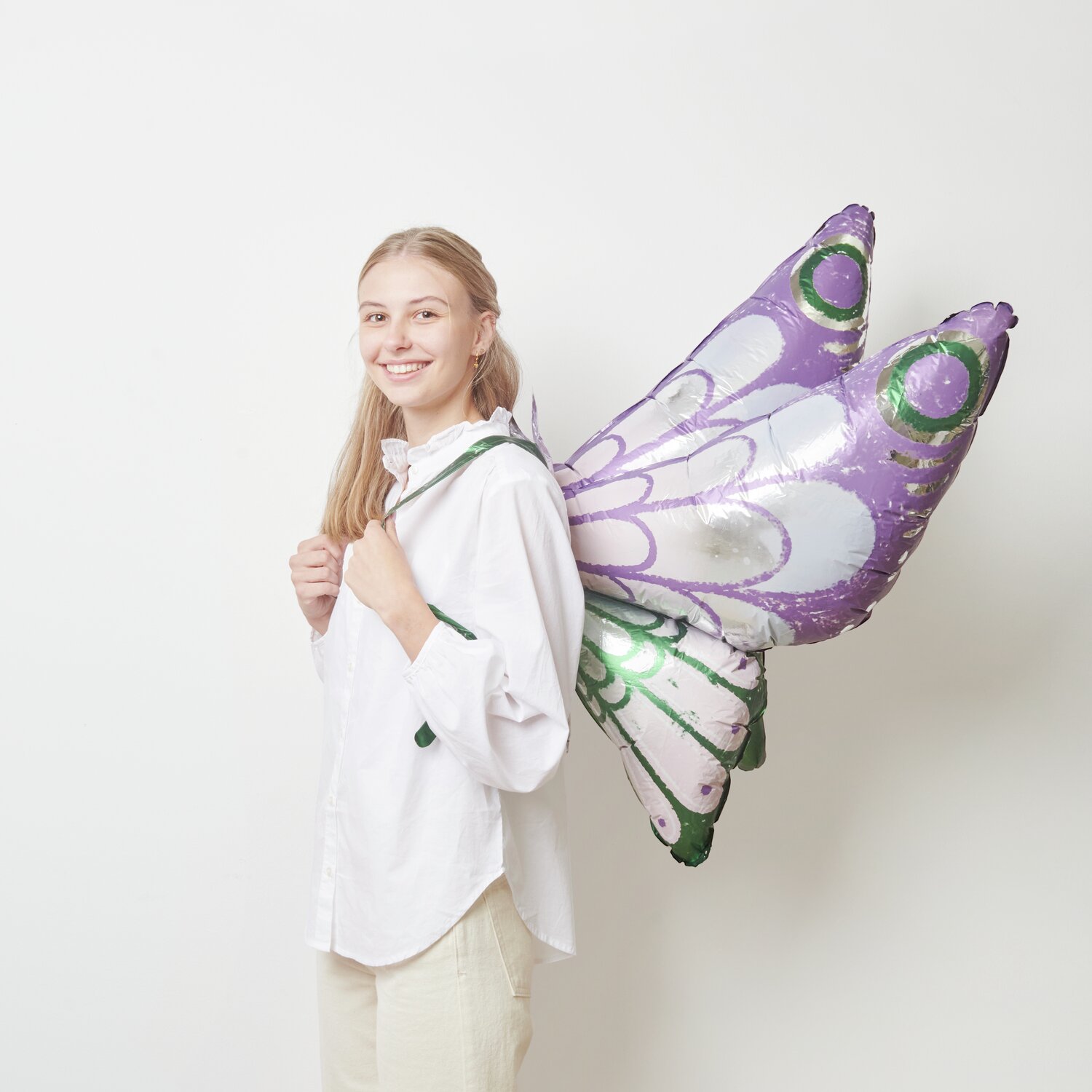 Folienballon Schmetterling zum Umbinden in Lila-Grün von Rico Design, getragen von einer Person.
