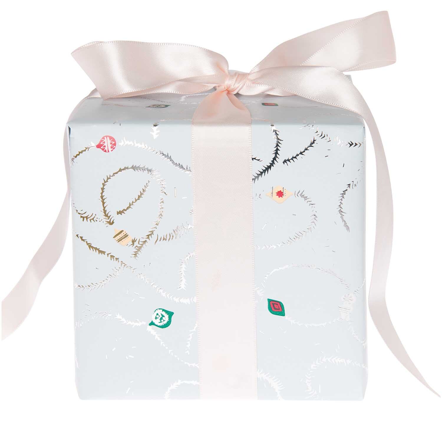 Paper Poetry Geschenkpapier Nostalgic Christmas mit Baumschmuck-Design in Blau, verziert mit Hot Foil, umwickelt um ein Geschenk mit rosa Schleife.