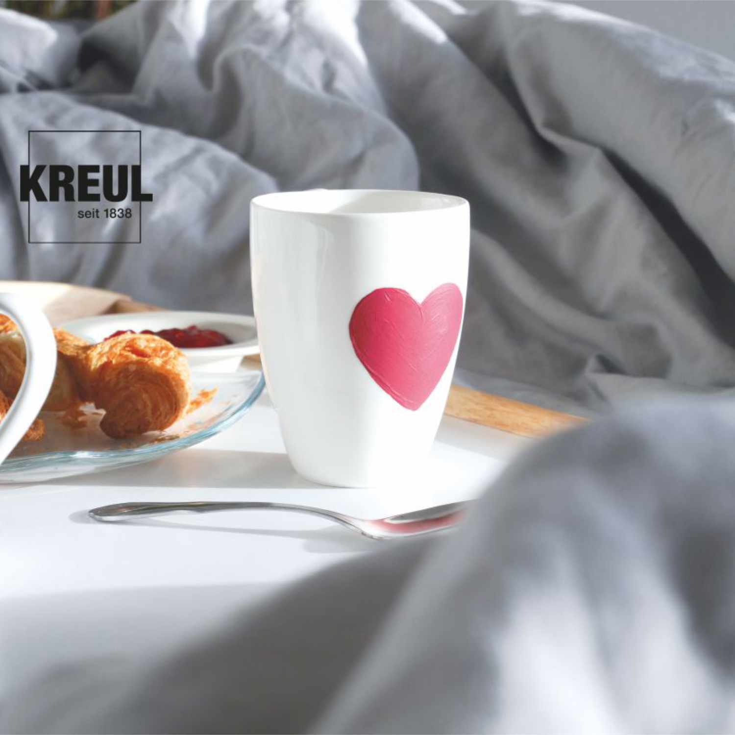 Glas- und Porzellanfarben Set Chalky: Weißer Becher mit rotem Herzmotiv, Frühstücksszene im Hintergrund.
