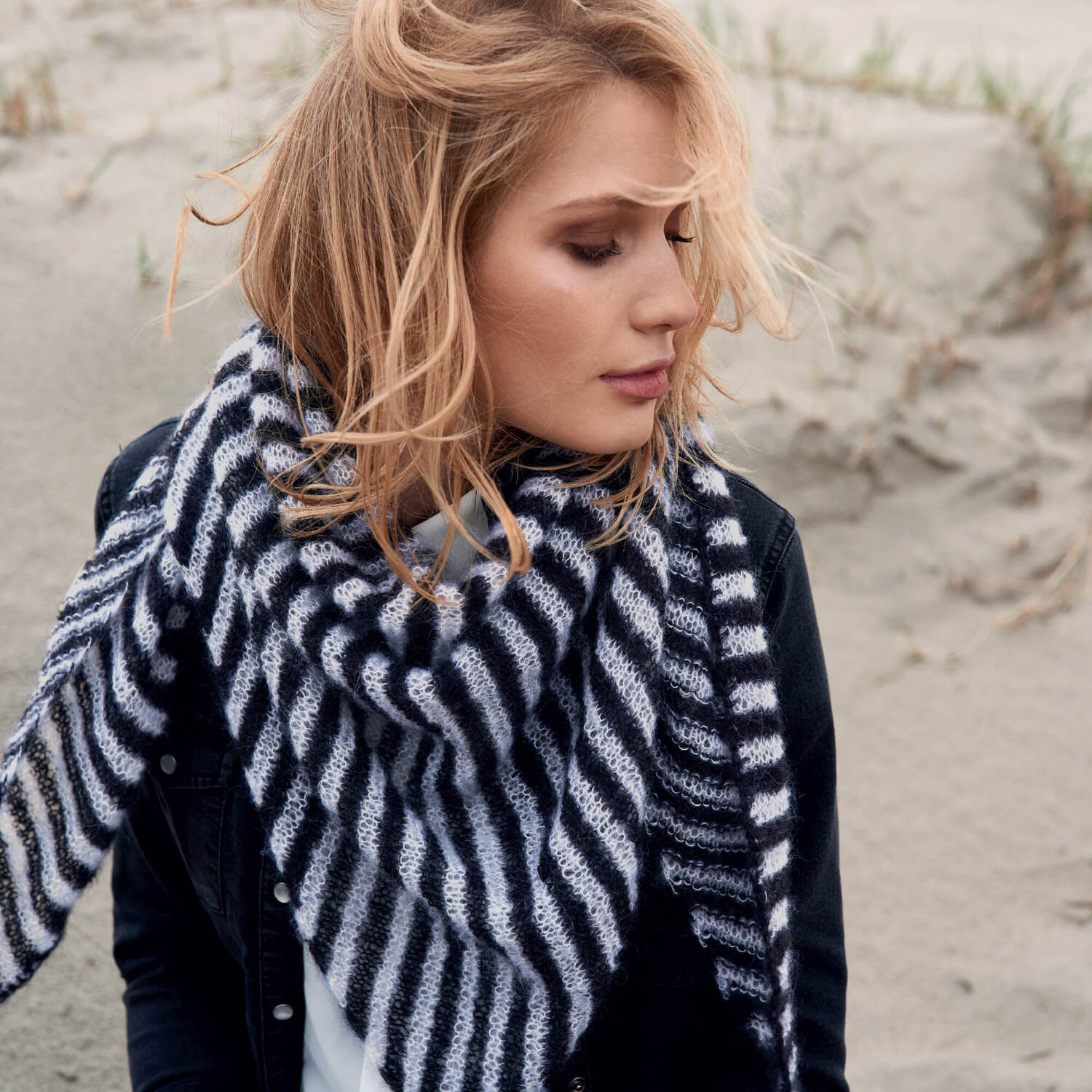 Strickanleitung Essentials Super Kid Mohair Loves Silk: Frau mit gestreiftem Schal am Strand.