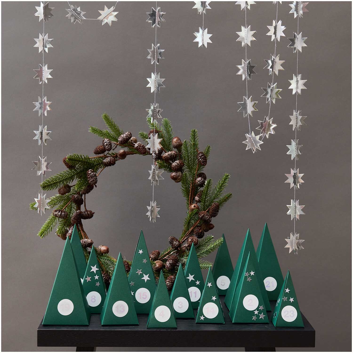 Paper Poetry Adventskalender Bäume von Rico Design: Grüne Baumformen mit Sternen und Kranz.