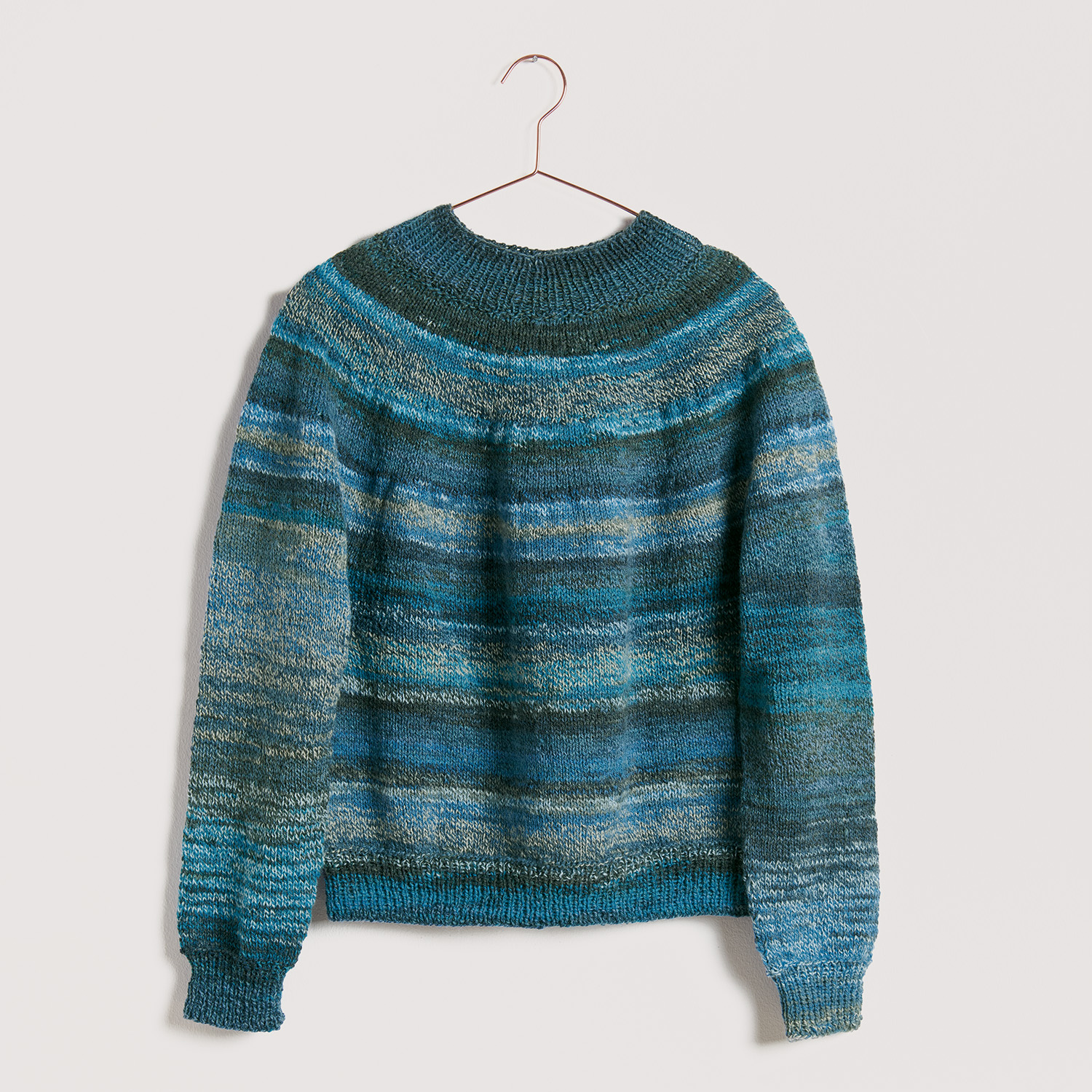 Blauer Pullover auf grauem Hintergrund – zum Strickset