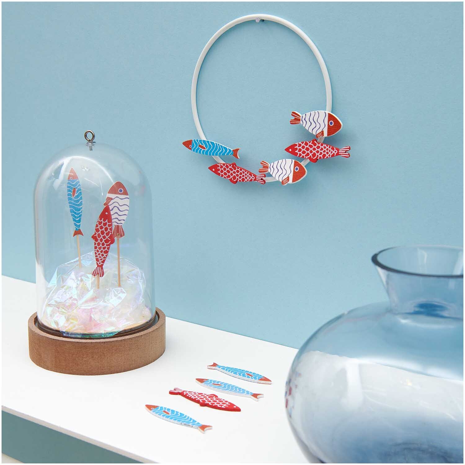 Deko-Picker Fisch Mix in rot-blau von Rico Design, dekorativ in Glasglocke und an Wand arrangiert.