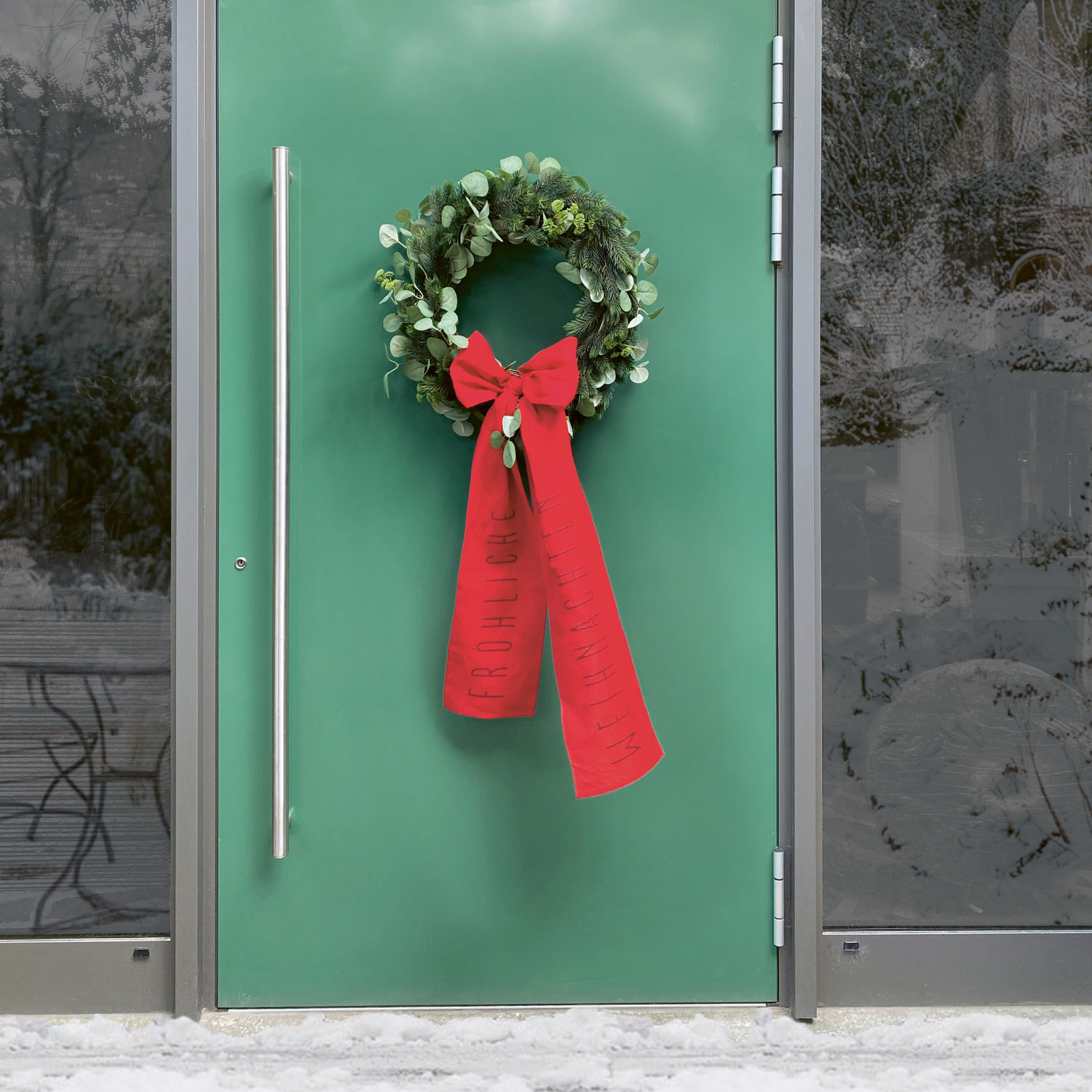 Stickbuch Put a Bow on It Nr. 185: Kranz mit roter Schleife an grüner Tür, weihnachtlich dekoriert.