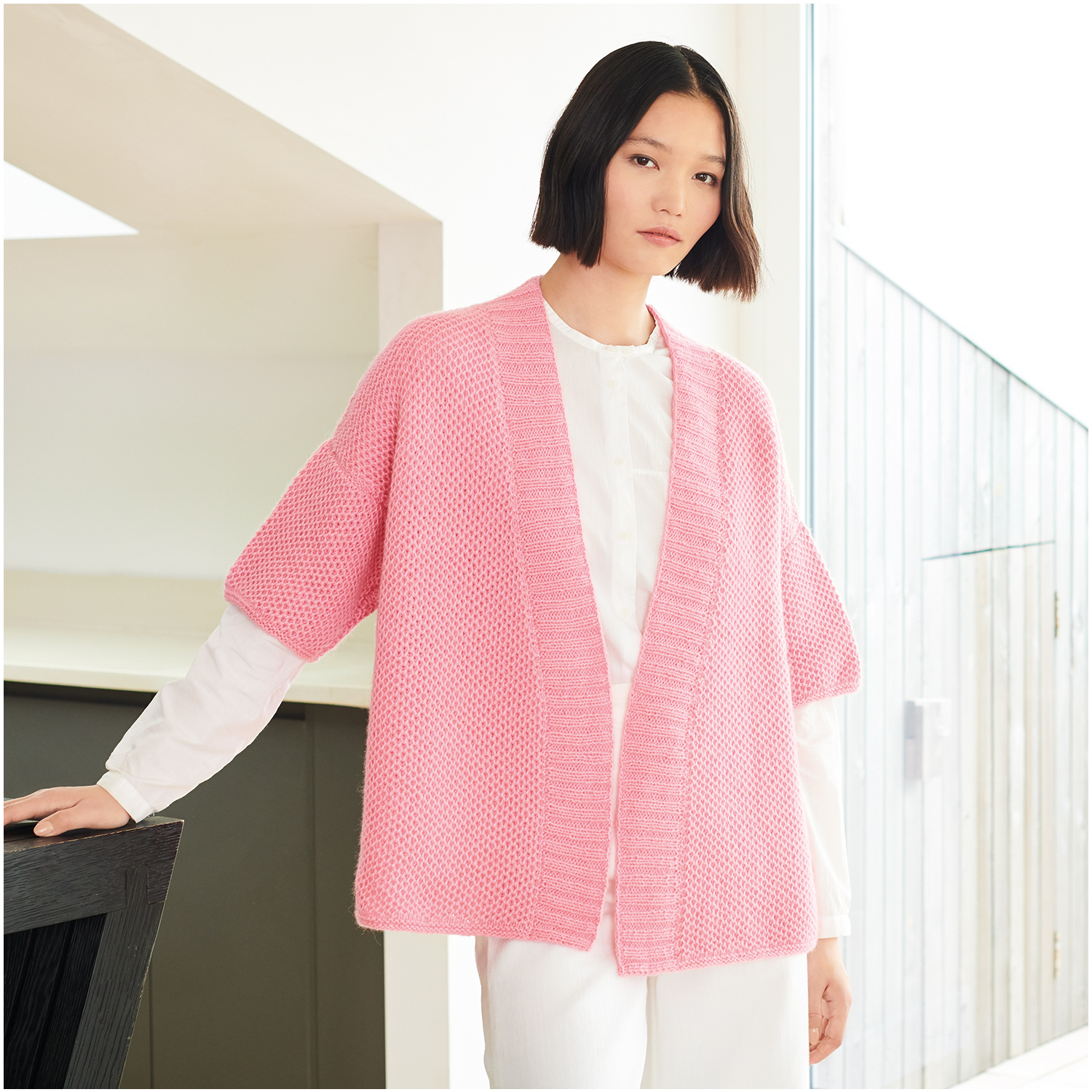 Strickset Kimono Modell 17: Eleganter rosa Kimono aus Lovewool Nr. 18, getragen von Frau in modernem Raum.