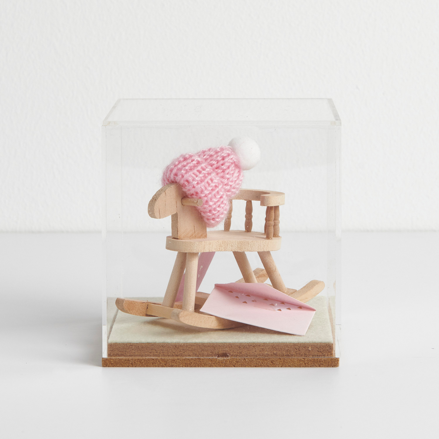Figurico Dekohaube Würfel mit einem Mini-Holzschaukelstuhl und rosa Strickmütze von Rico Design.