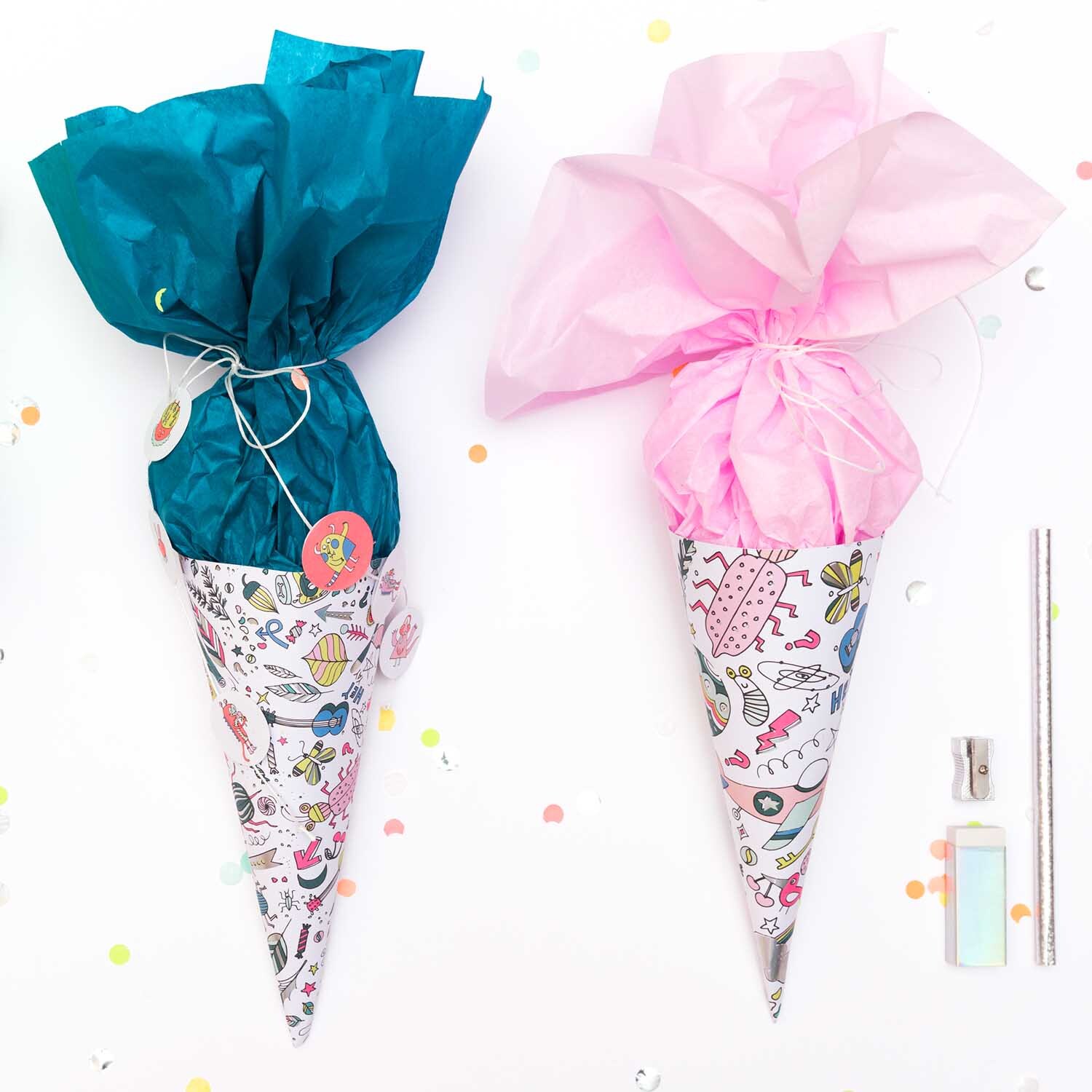 Bastelanleitung Mini-Schultüten aus Motivpapier: Zwei bunte Schultüten mit blauem und rosa Papier, dekoriert mit Mustern.
