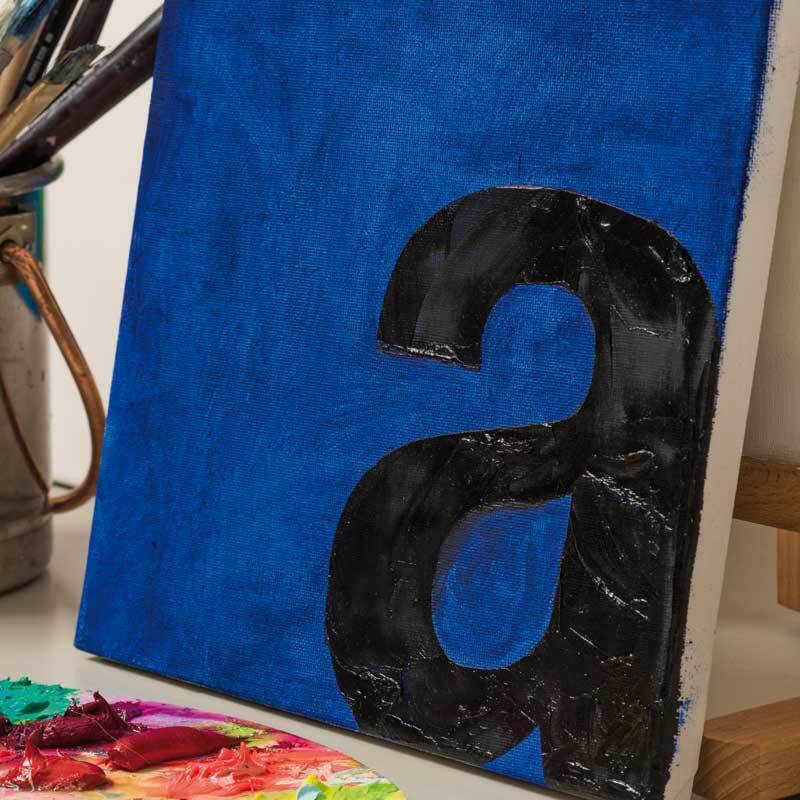 Prato Ölfarbe von Rico Design: Ein blaues Gemälde mit schwarzem Buchstaben, umgeben von Malutensilien.
