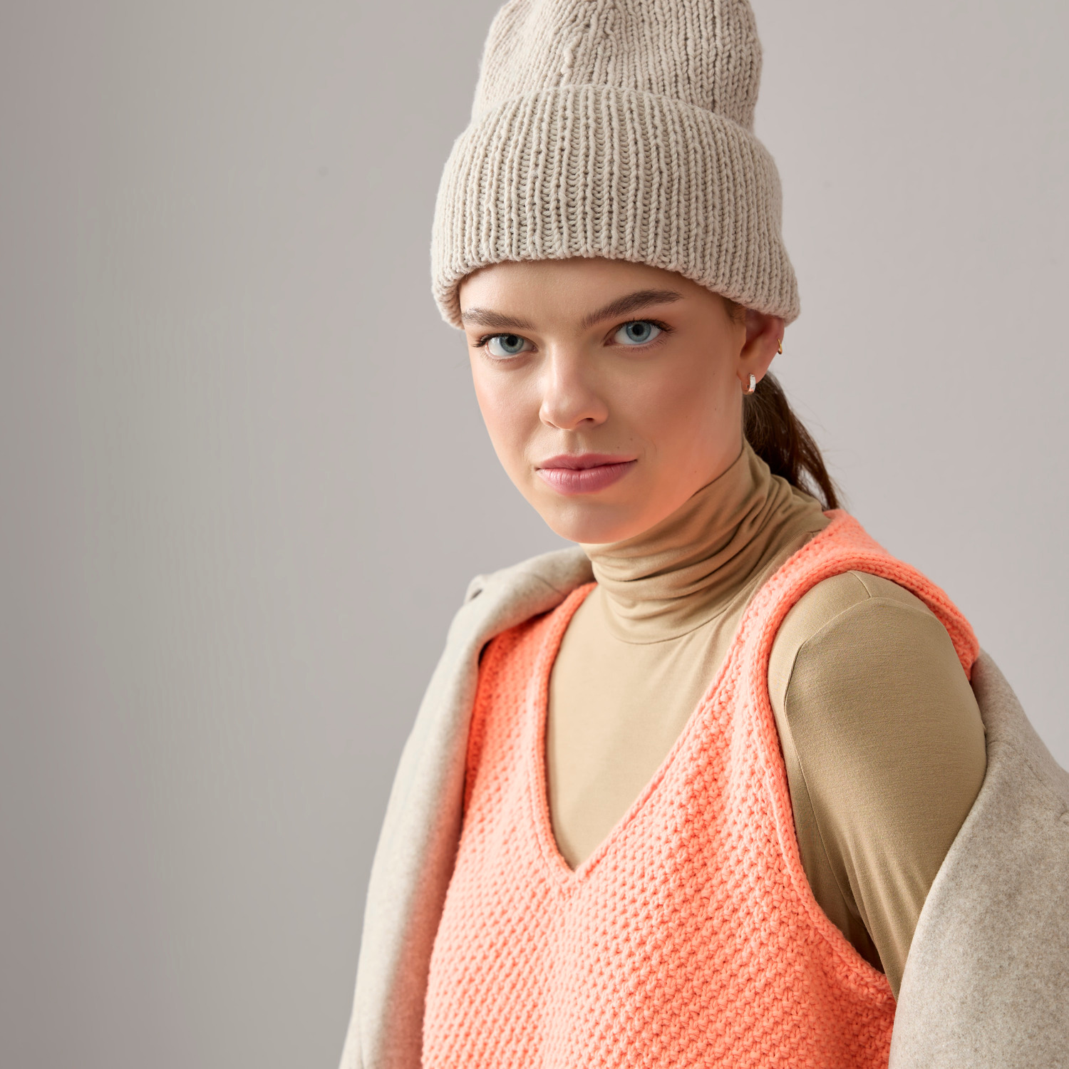 Vegan Cashmere Special: Frau trägt beige Mütze und orangefarbenen Pullover von Rico Design.
