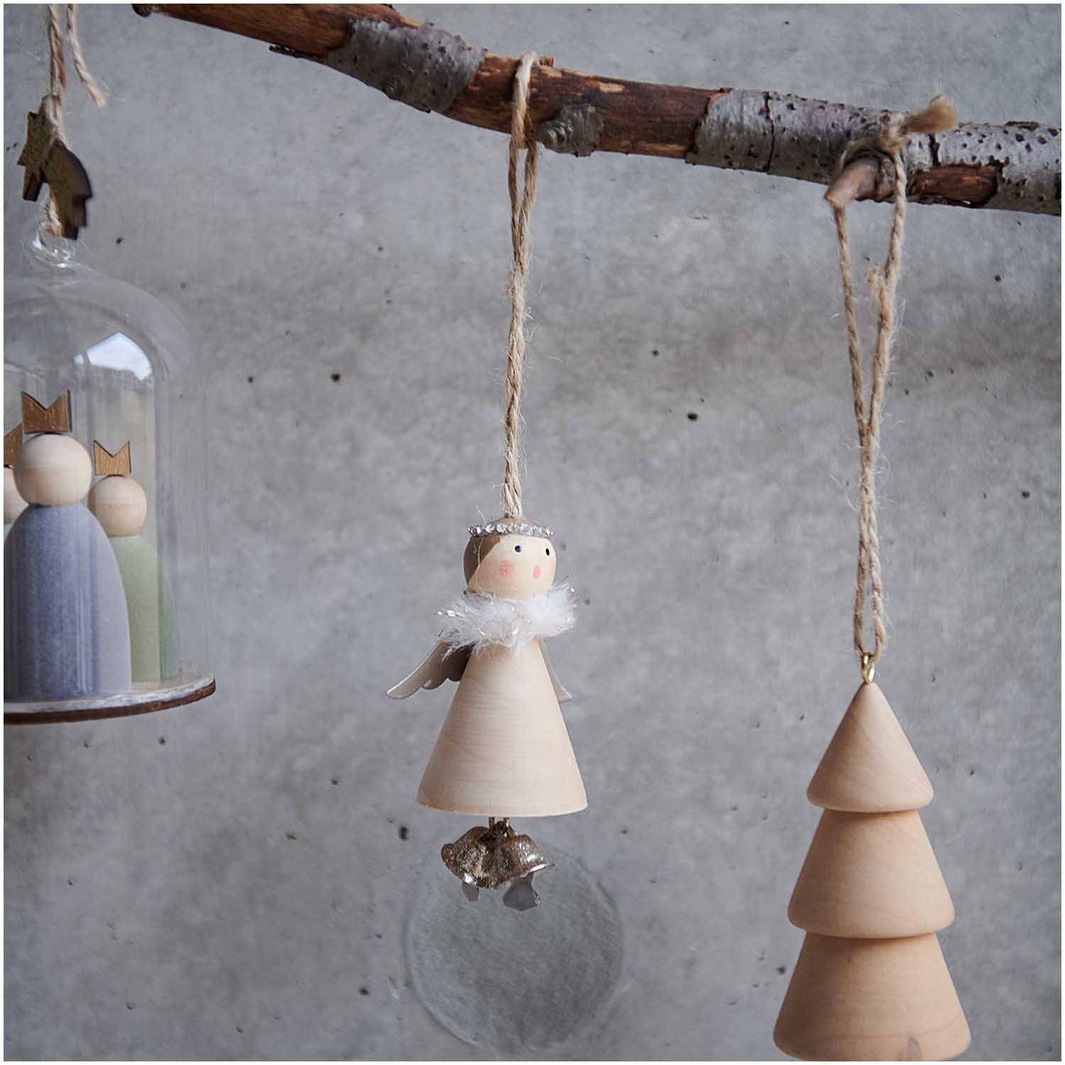 Holzhänger Engel mit Glöckchen natur 8cm: Dekorativer Holzengel mit Glöckchen, hängend an einem Ast, ideal für weihnachtliche Dekorationen.