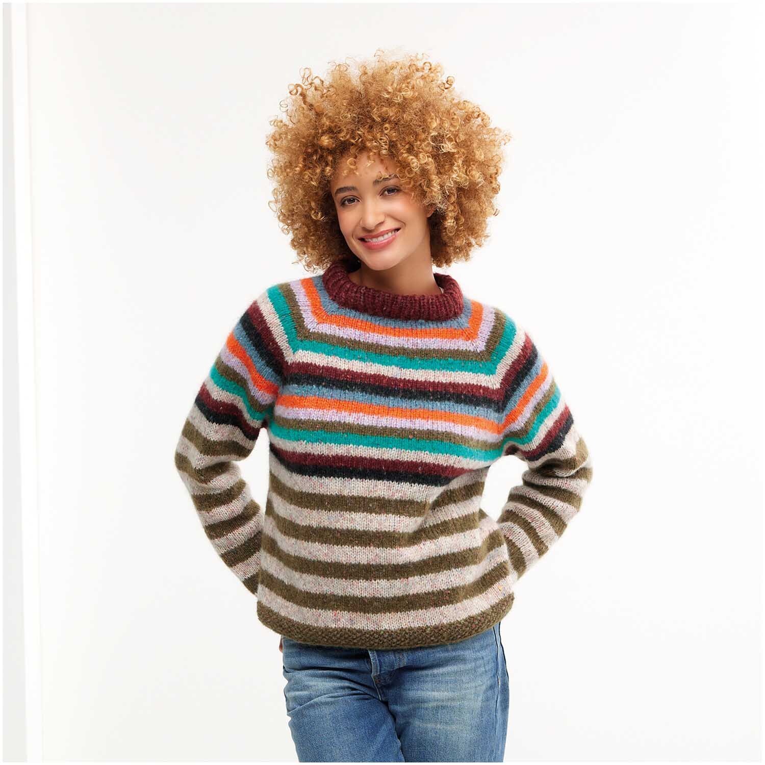 Strickset Pullover Modell 19: Frau trägt gestreiften Pullover in bunten Farben, lächelt und steht vor weißem Hintergrund.
