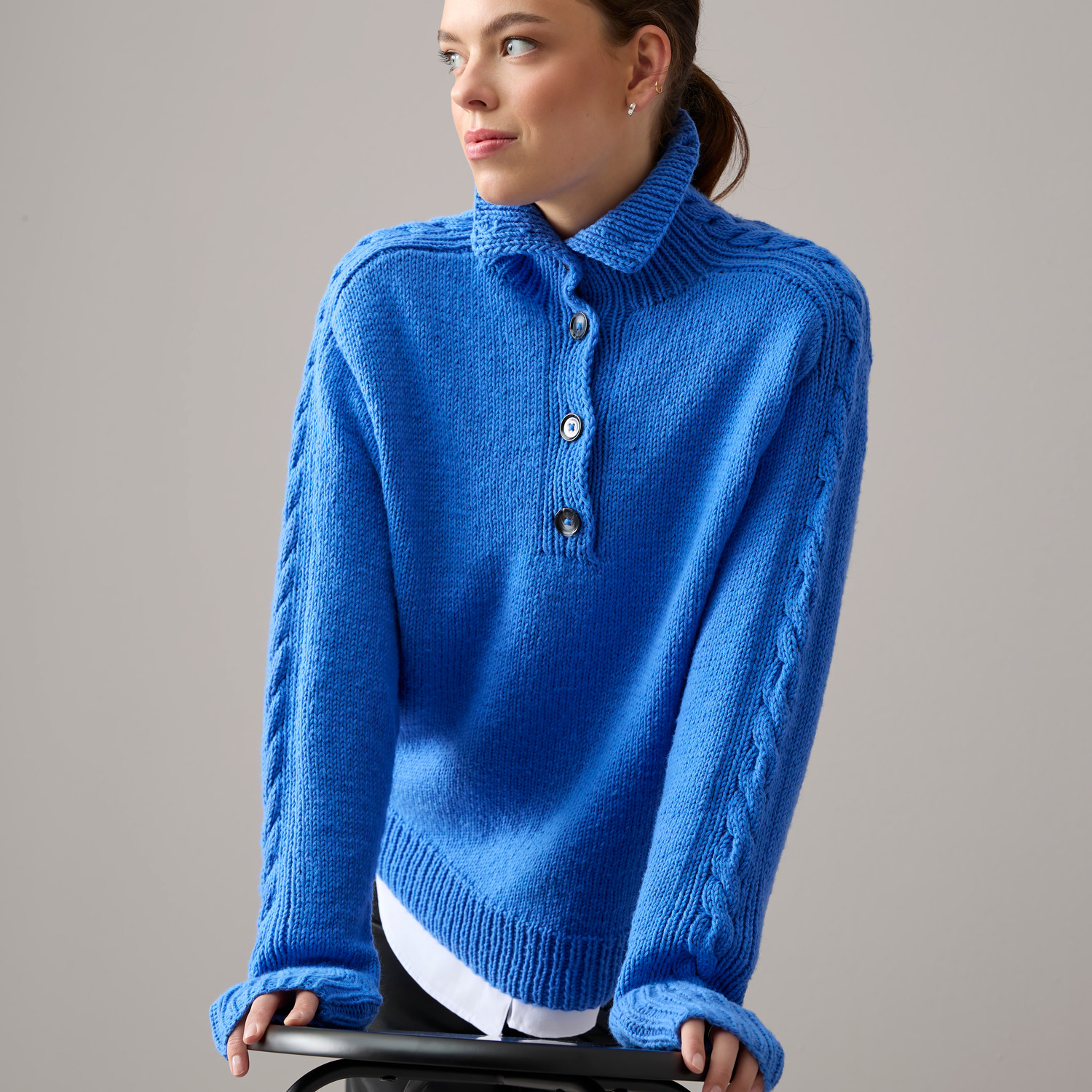 Vegan Cashmere Special: Frau trägt blauen Strickpullover von Rico Design mit Zopfmuster und Knopfleiste.