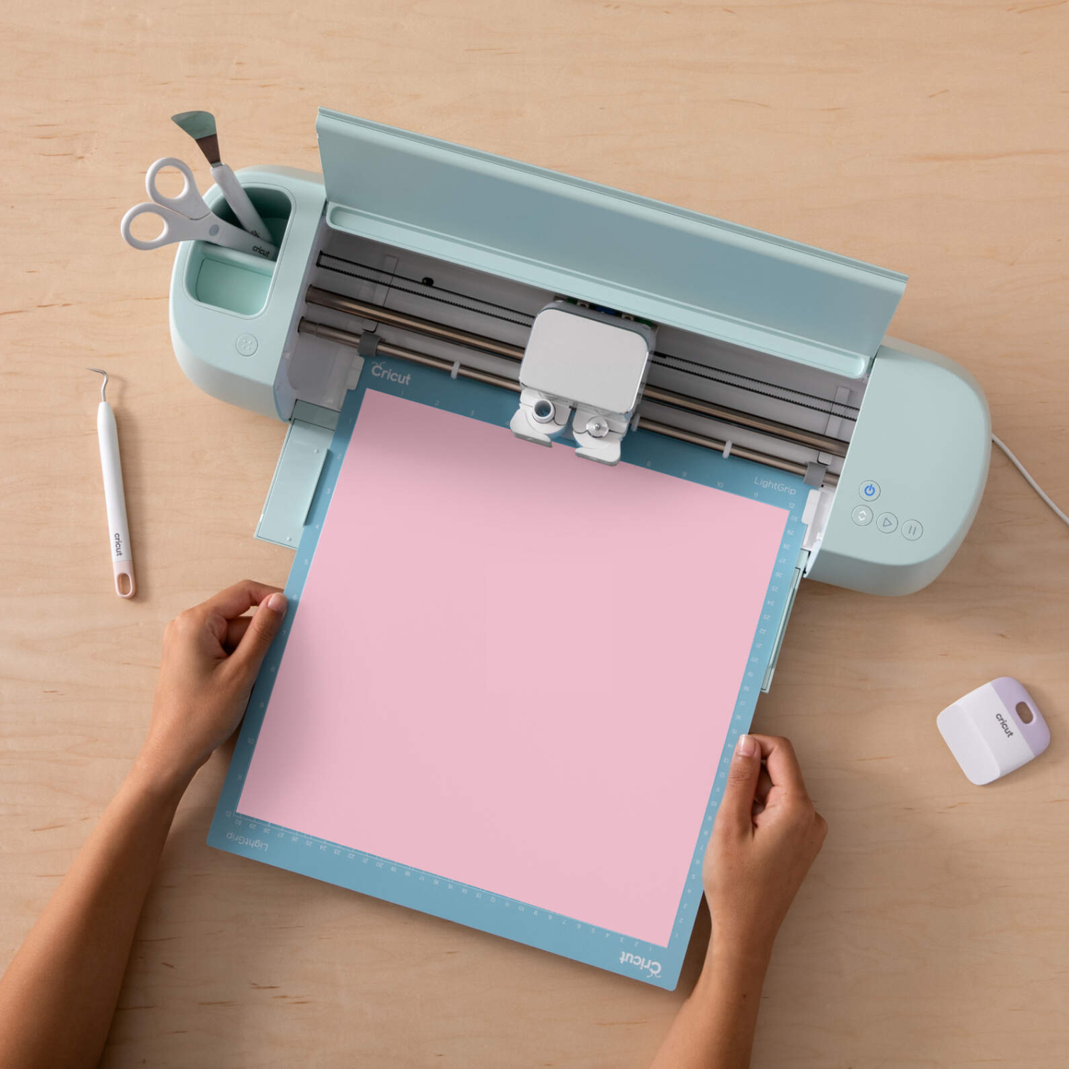 Color change Vinyl COLD Permanent: Eine Person legt rosa Vinylfolie in eine Cricut-Schneidemaschine ein.