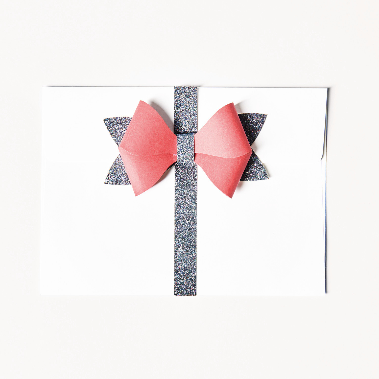 Paper Poetry Bastelpapierblock Put a Bow on It: Weißes Papier mit roter Schleife und glitzerndem Band, ideal für kreative Projekte.