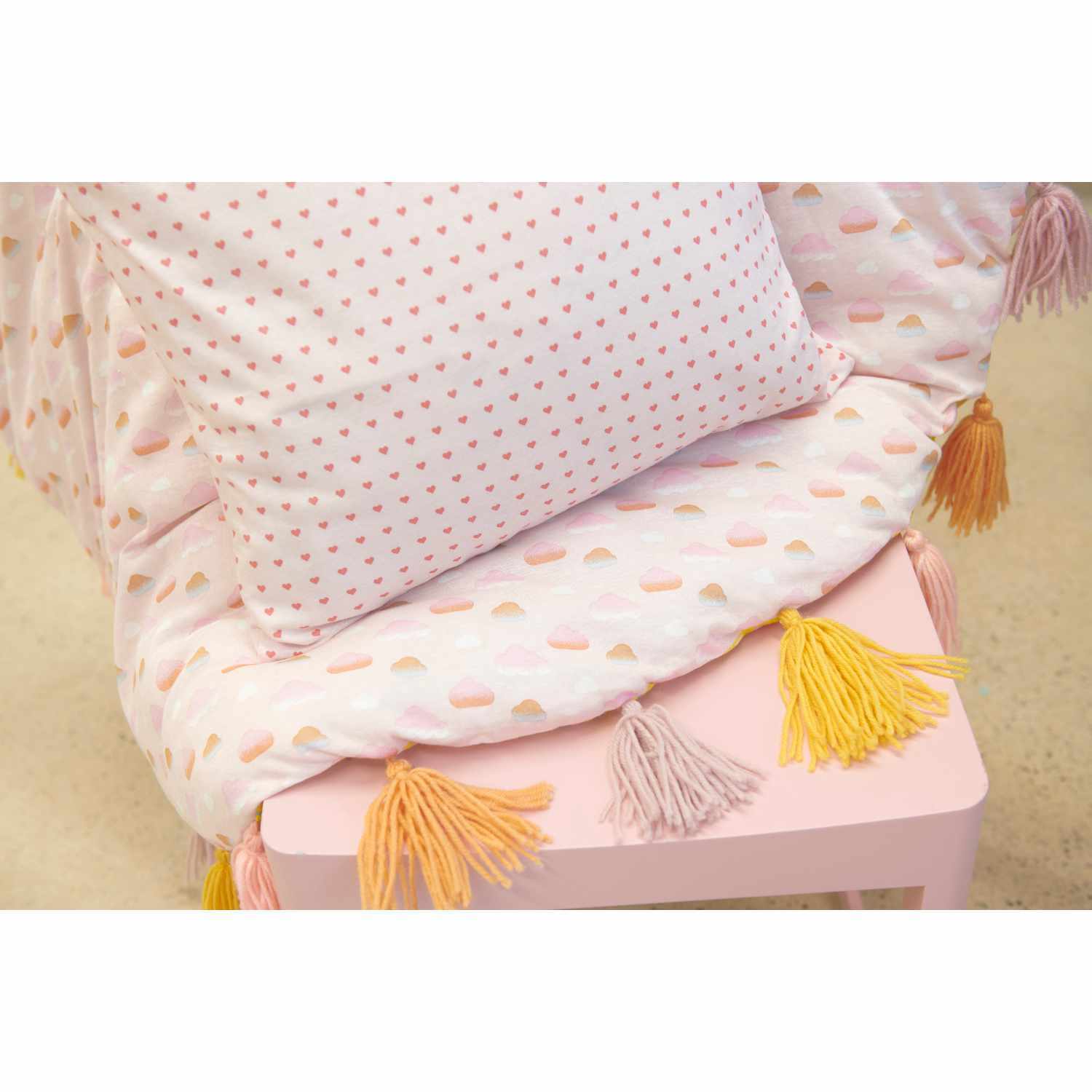 Jerseystoff Happy Baby Herzchen in Rosa von Rico Design, dekoriert mit Kissen und Quasten.