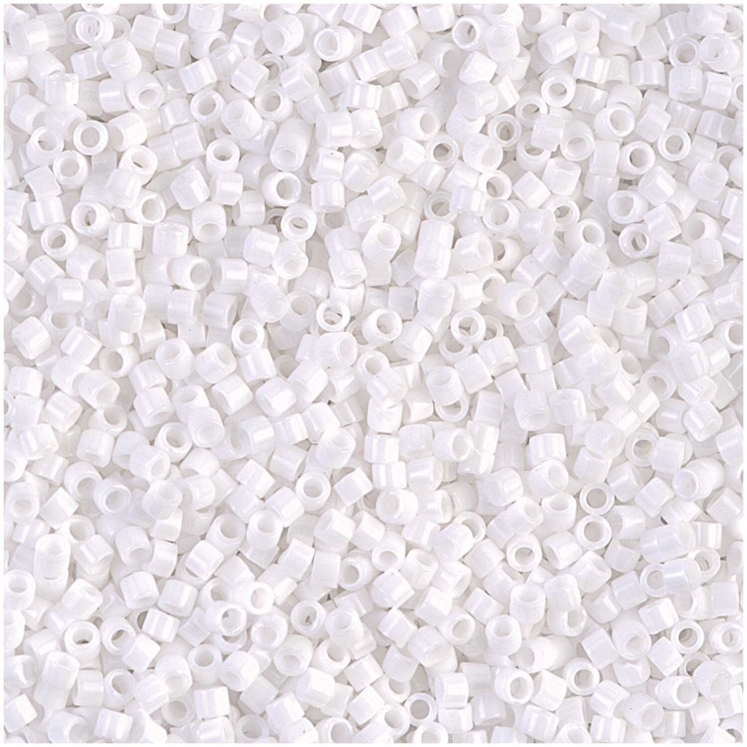 itoshii tube Perlen 2mm 7g von Rico Design in Weiß Opak, verstreut auf einer Fläche. Ideal für kreative Bastelprojekte.