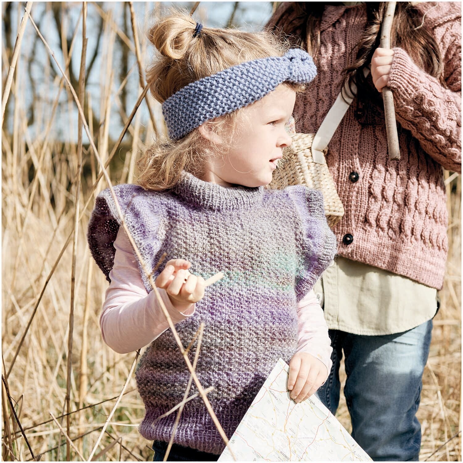Creative Melange Garzato aran Wonderball: Kind im flieder-türkisen Strickpullunder mit Karte.