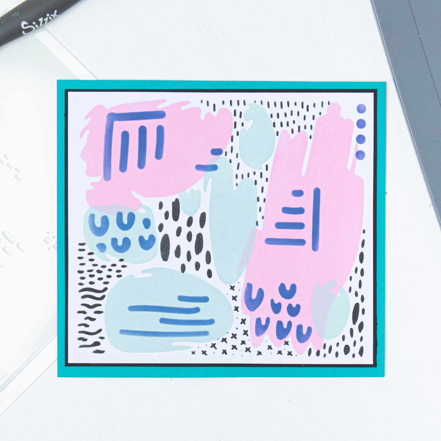 Layered Stencils Abstract Marks von Sizzix: Bunte Schablonen mit abstrakten Mustern in Rosa, Blau und Schwarz auf weißem Hintergrund.