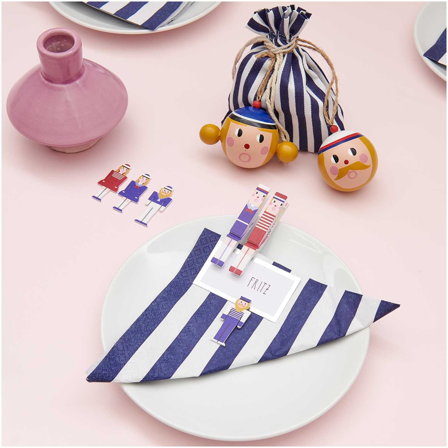 Dekoklammern Seeleute Mix auf gestreiftem Tuch, umgeben von maritimen Accessoires, von Rico Design.
