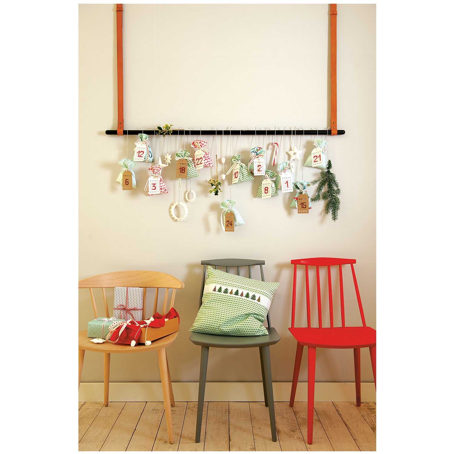 Stoff Winterimpressionen rot 50x140cm von Rico Design, dekoriert mit Adventskalender über drei Stühlen in verschiedenen Farben.