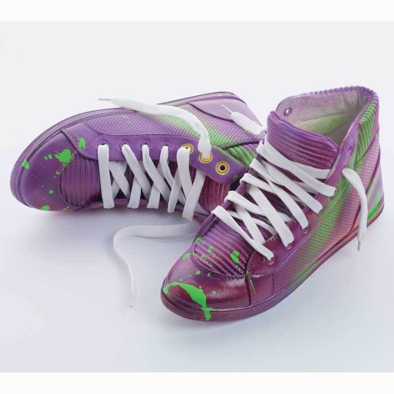 Lila Sneaker mit grünen Farbspritzern und weißen Schnürsenkeln auf weißem Hintergrund.