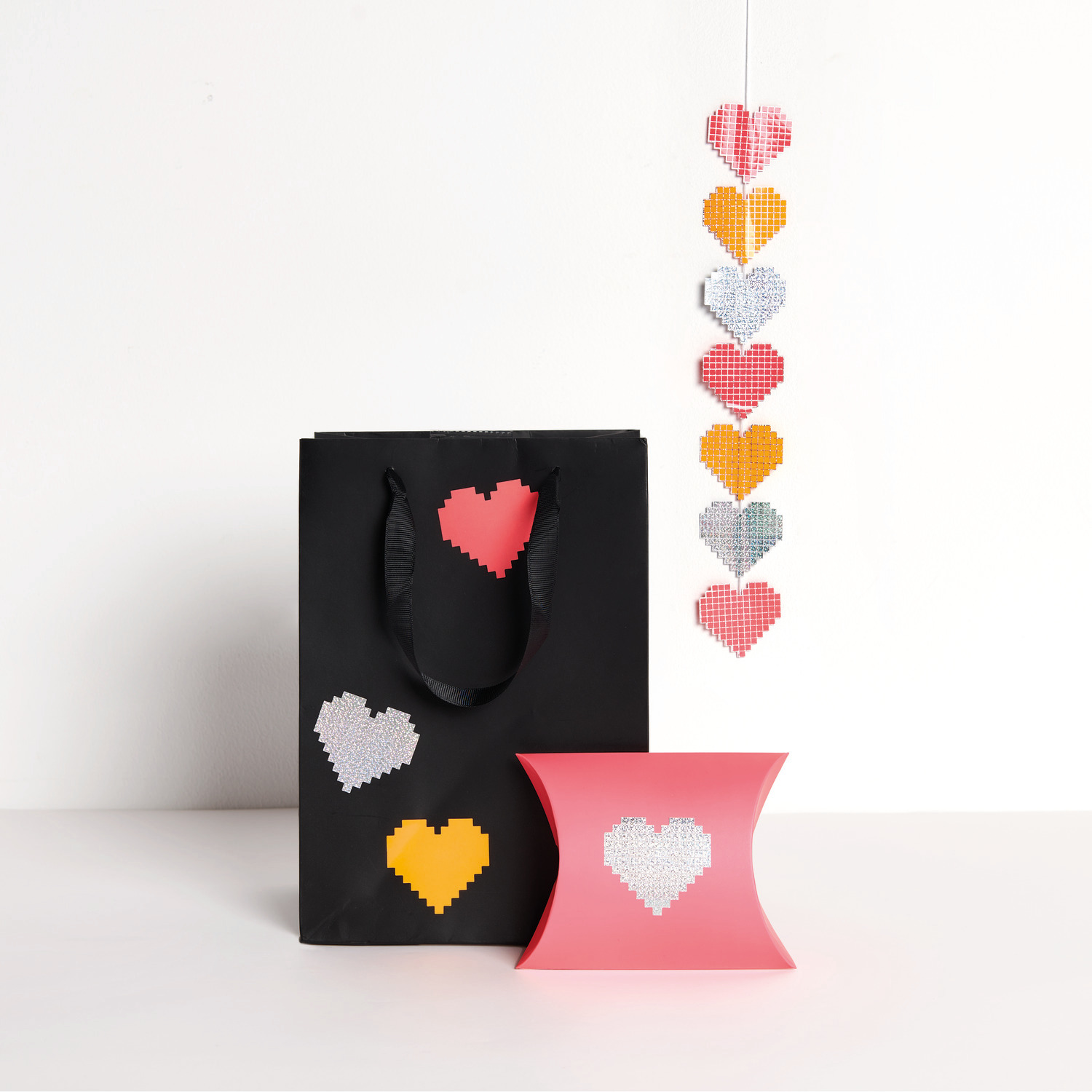 Paper Poetry Sticker Herzen auf der Rolle: Schwarze Tasche und rosa Box mit Herzmotiven, dekorativ arrangiert.