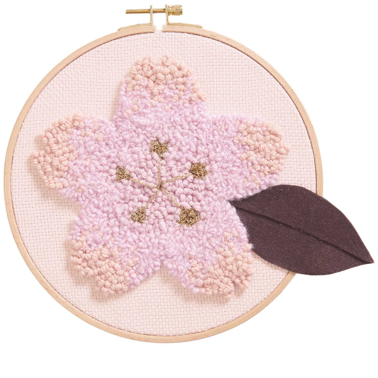 Punch Needle Packung Bild zeigt eine Kirschblüte in Braun mit einem dunklen Blatt, von Rico Design.