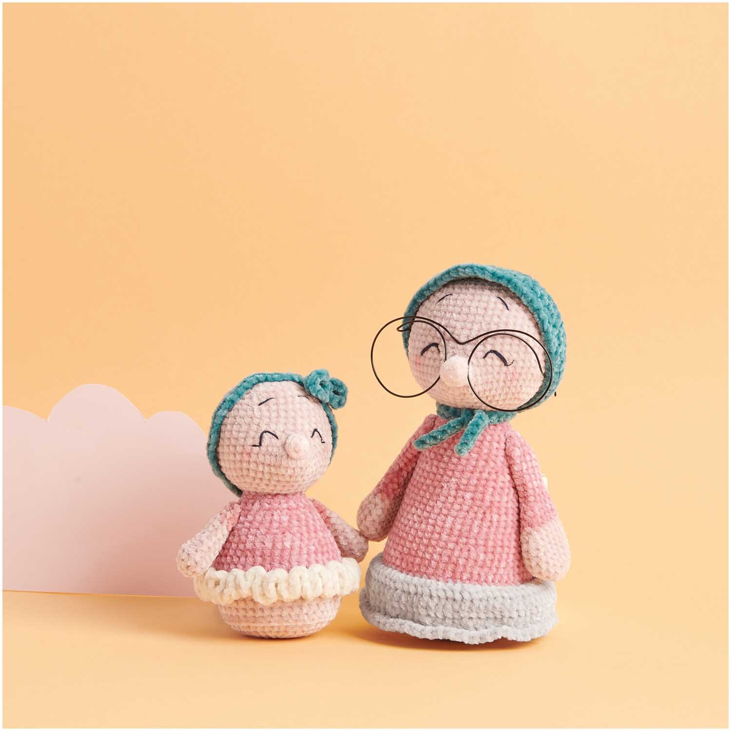 Ricorumi Nilli Nilli: Zwei gehäkelte Figuren in Rosa mit blauen Details, eine trägt eine Brille.