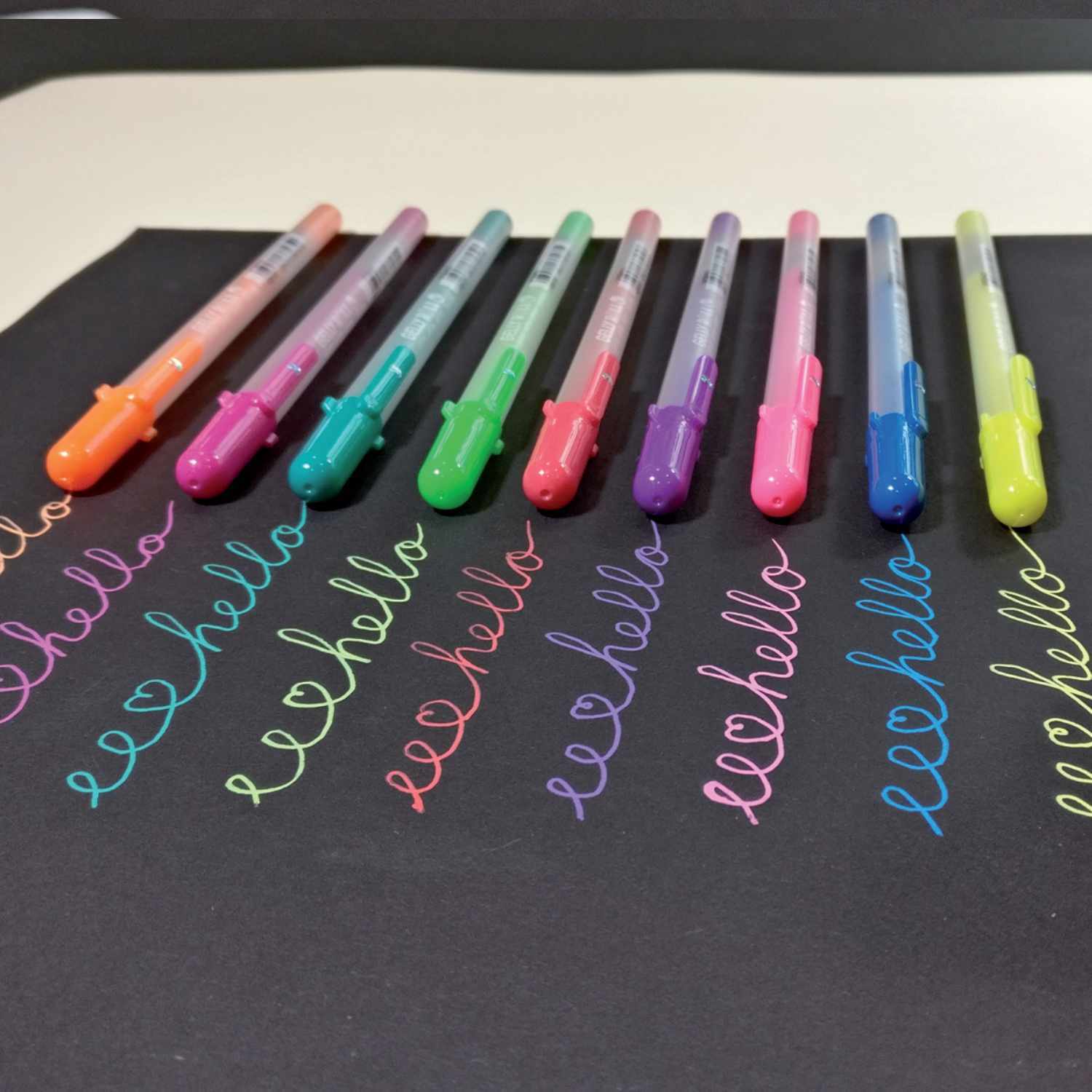 Gelly Roll Moonlight Gelstift: Bunte Stifte auf schwarzem Papier, ideal für kreative Projekte.