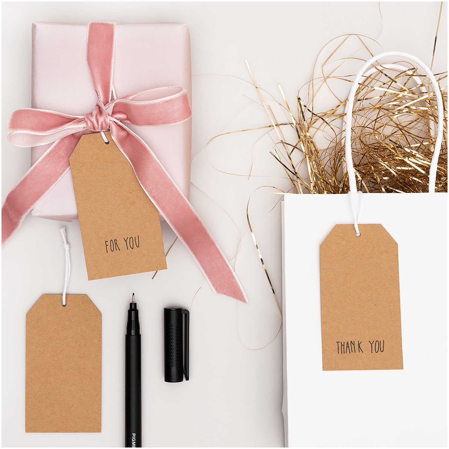 Paper Poetry Papieranhänger Kraftpapier 24 Stück, dekoriert mit rosa Geschenkband und weißer Geschenktüte, ideal für kreative Verpackungen.