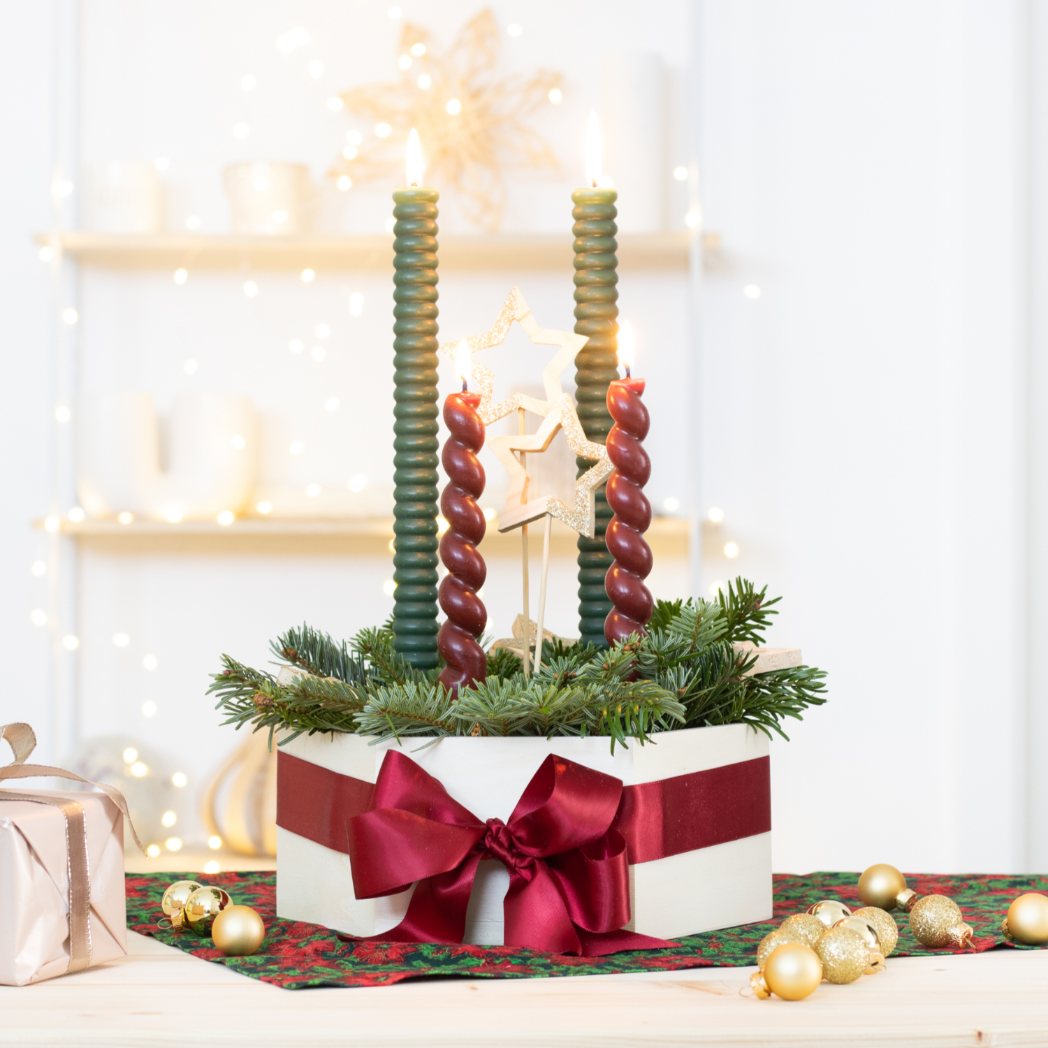 Bastelanleitung Adventskranz by machsschoen: Ein festlicher Adventskranz mit grünen und roten Kerzen, dekoriert mit Tannenzweigen und einer roten Schleife.