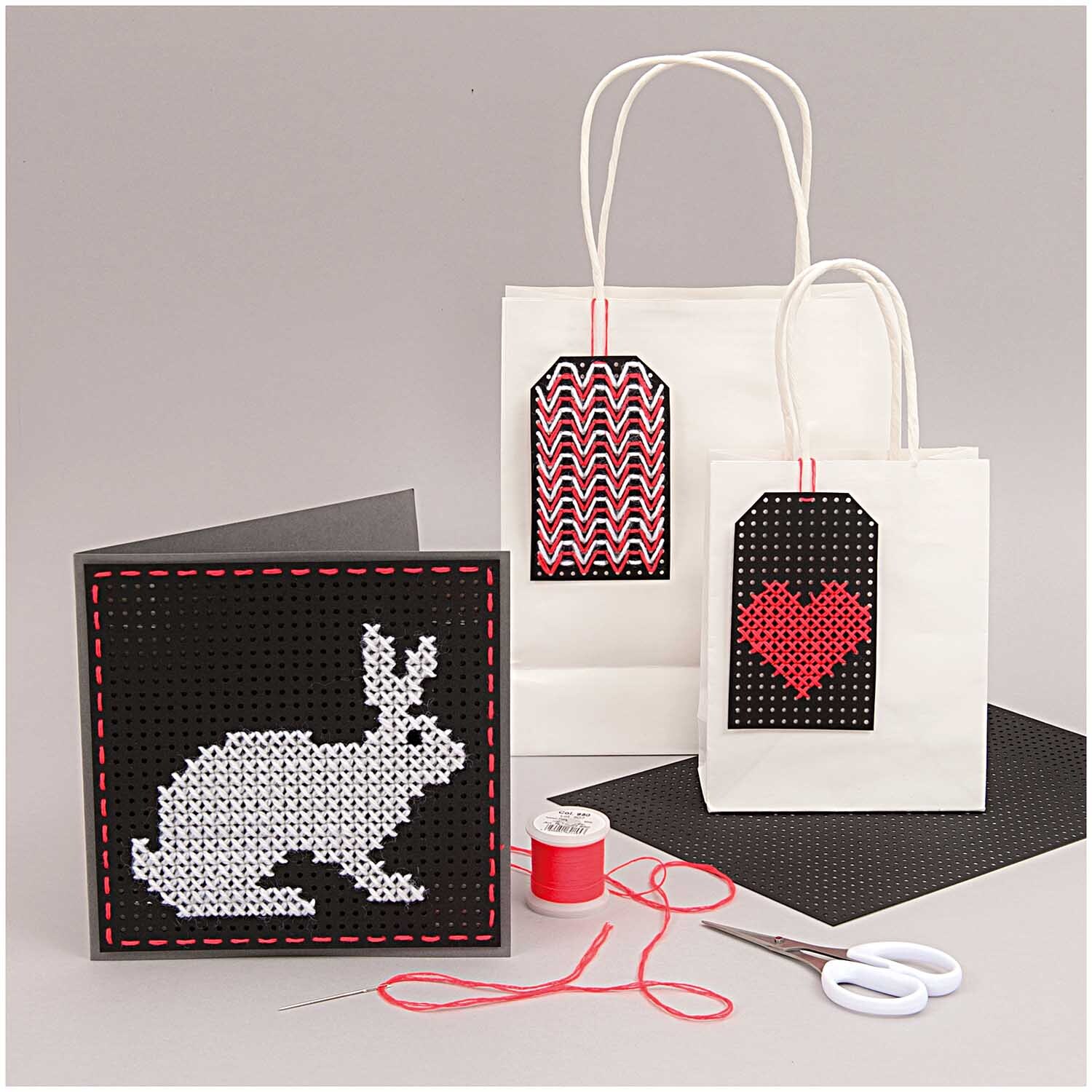 Paper Poetry Stickkarton zeigt kreative Stickmuster mit Hase und Herz auf Taschen und Karten. Ideal für DIY-Projekte.
