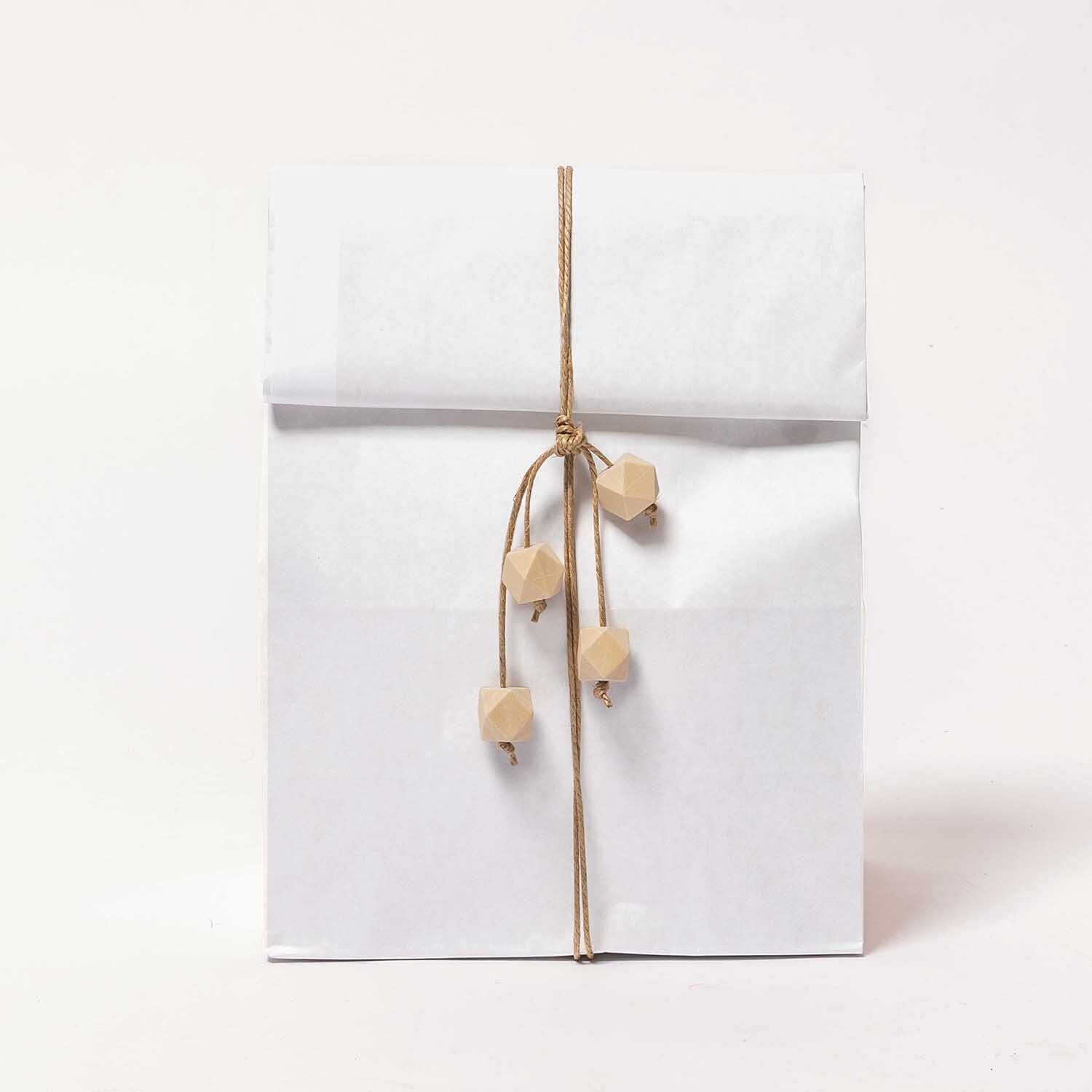 Paper Poetry Maxi-Blockbodenbeutel XL in Weiß mit dekorativem Band und Holzperlen. Ideal für stilvolle Geschenkverpackungen.