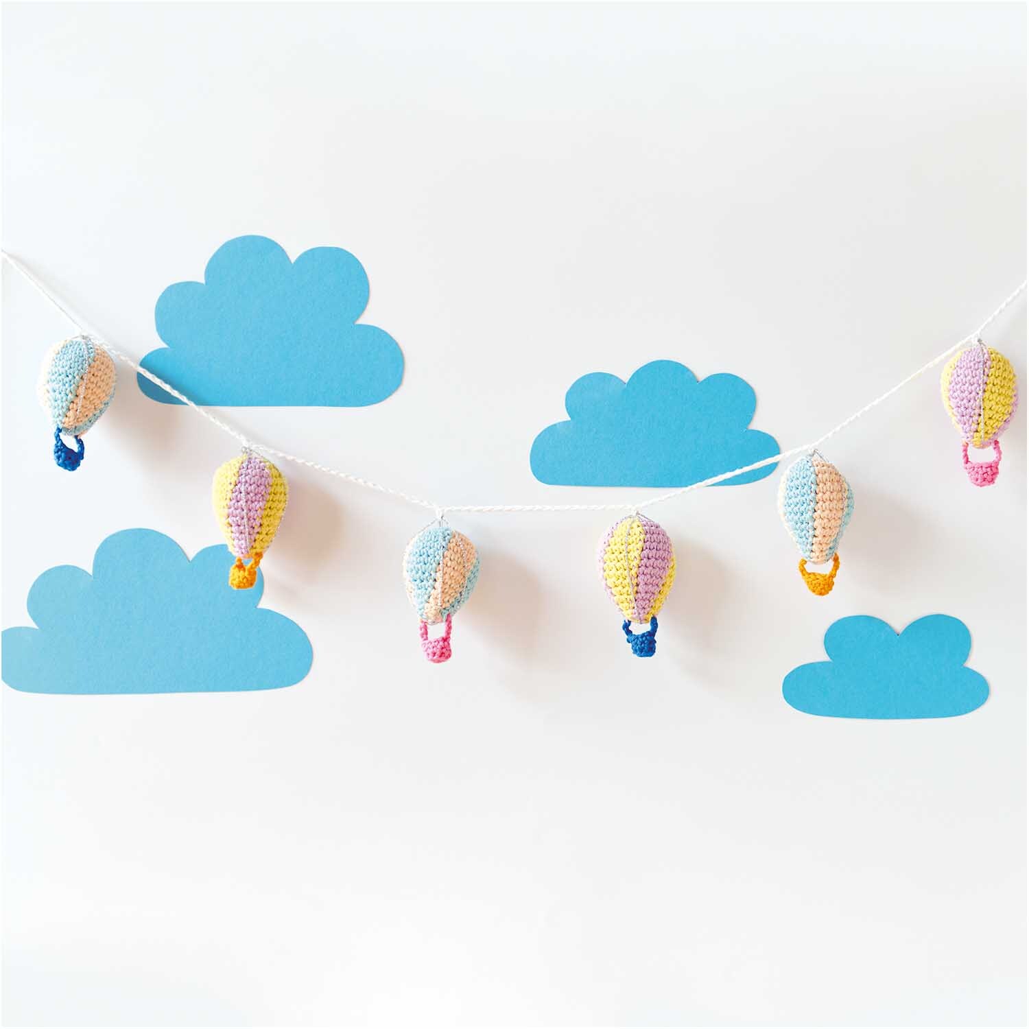 Creative Cotton aran: Bunte, gehäkelte Heißluftballons vor blauen Wolken, ideal für Dekorationen.