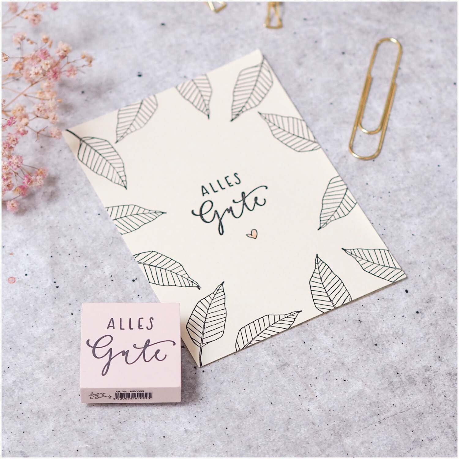 Stempel "Alles Gute" in Rosa von May&Berry neben einer Karte mit Blattmuster und Schriftzug.