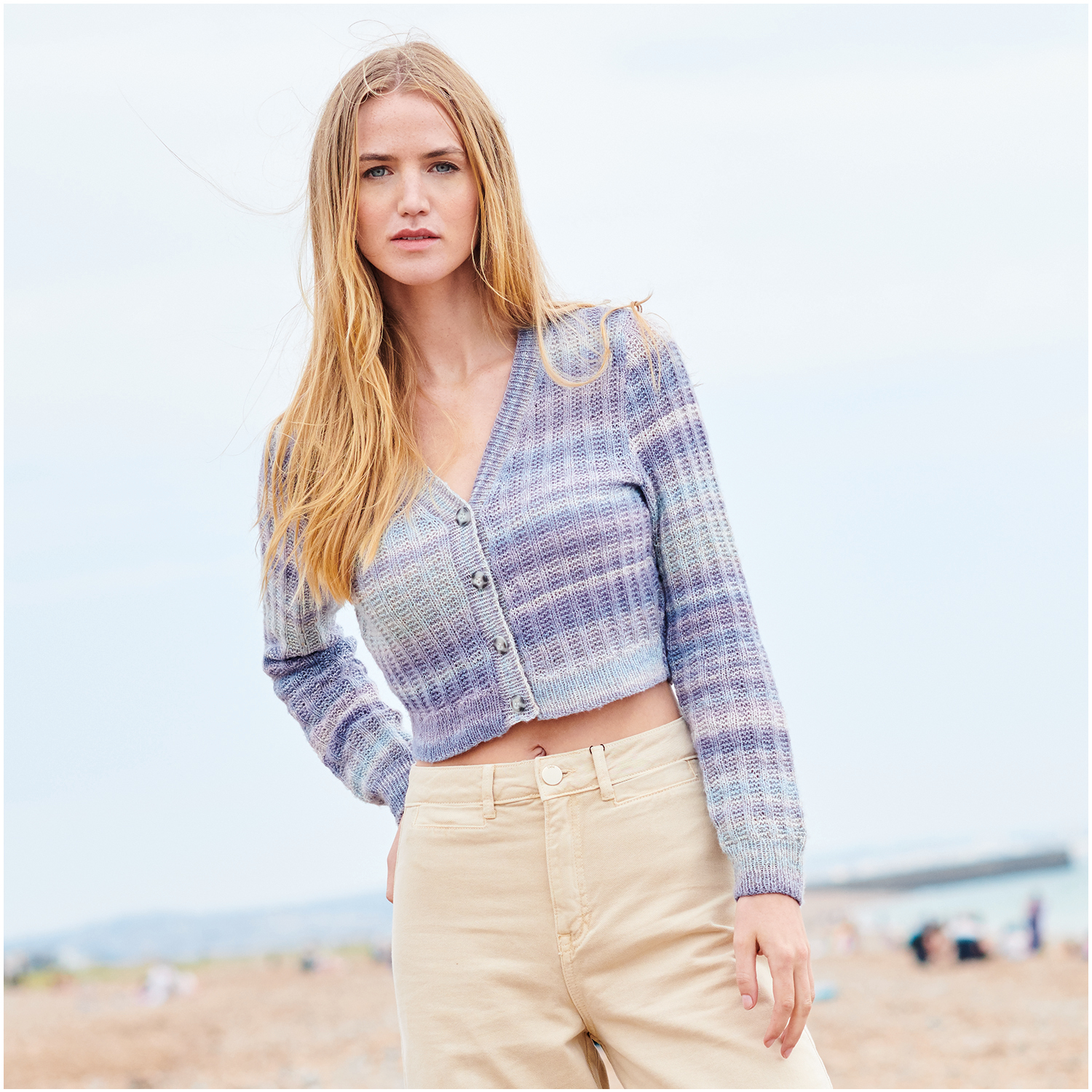 Strickset Jacke Modell 28 aus Lovewool Nr. 18: Frau trägt eine gestrickte, pastellfarbene Jacke am Strand.
