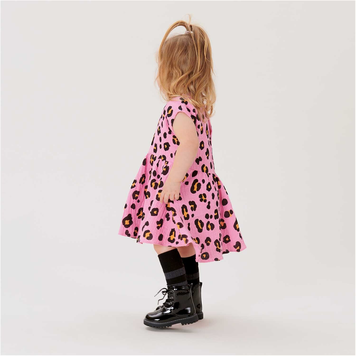 Stoffabschnitt Krinkelmusselin Acid Leo pink 50x130cm: Kind in rosa Kleid mit Leopardenmuster, schwarze Stiefel, seitlich stehend.