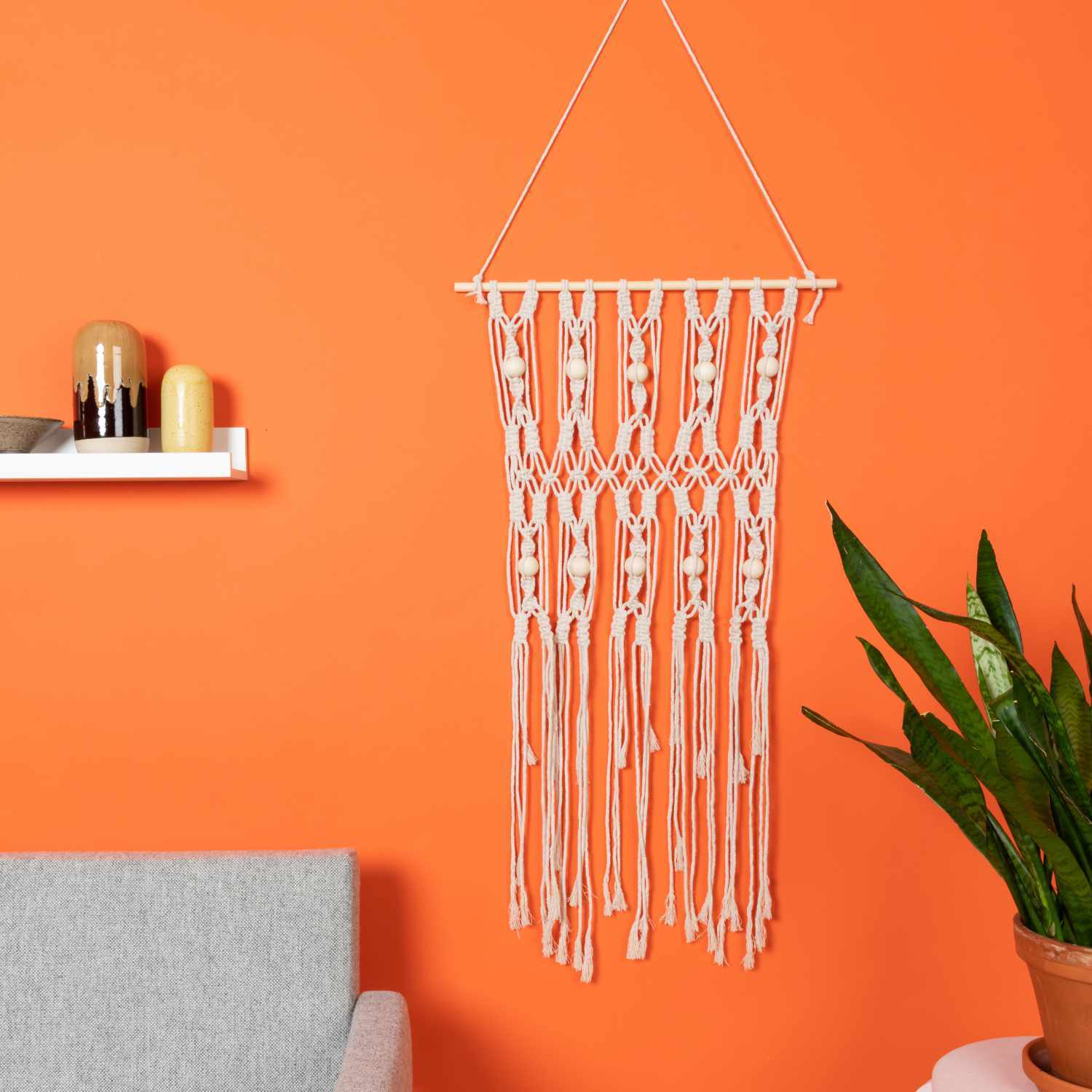 Baumwollkordel für Makramee 5mm 80m 500g, cremefarben, dekorativ an orangefarbener Wand hängend.