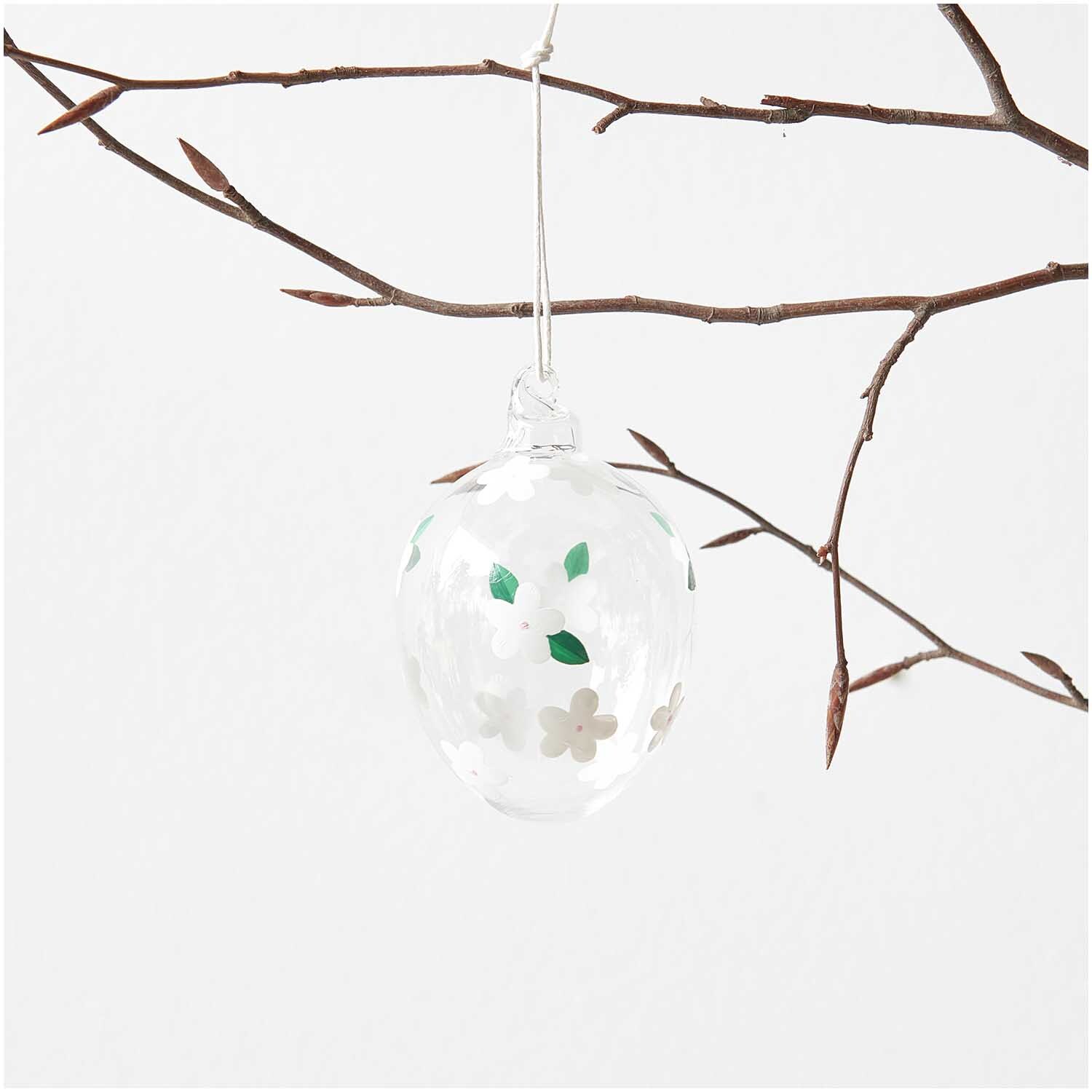 Glas Ei Erdbeerblüte handbemalt Ø 6cm von Rico Design, hängend an einem kahlen Ast, mit floralen Mustern.