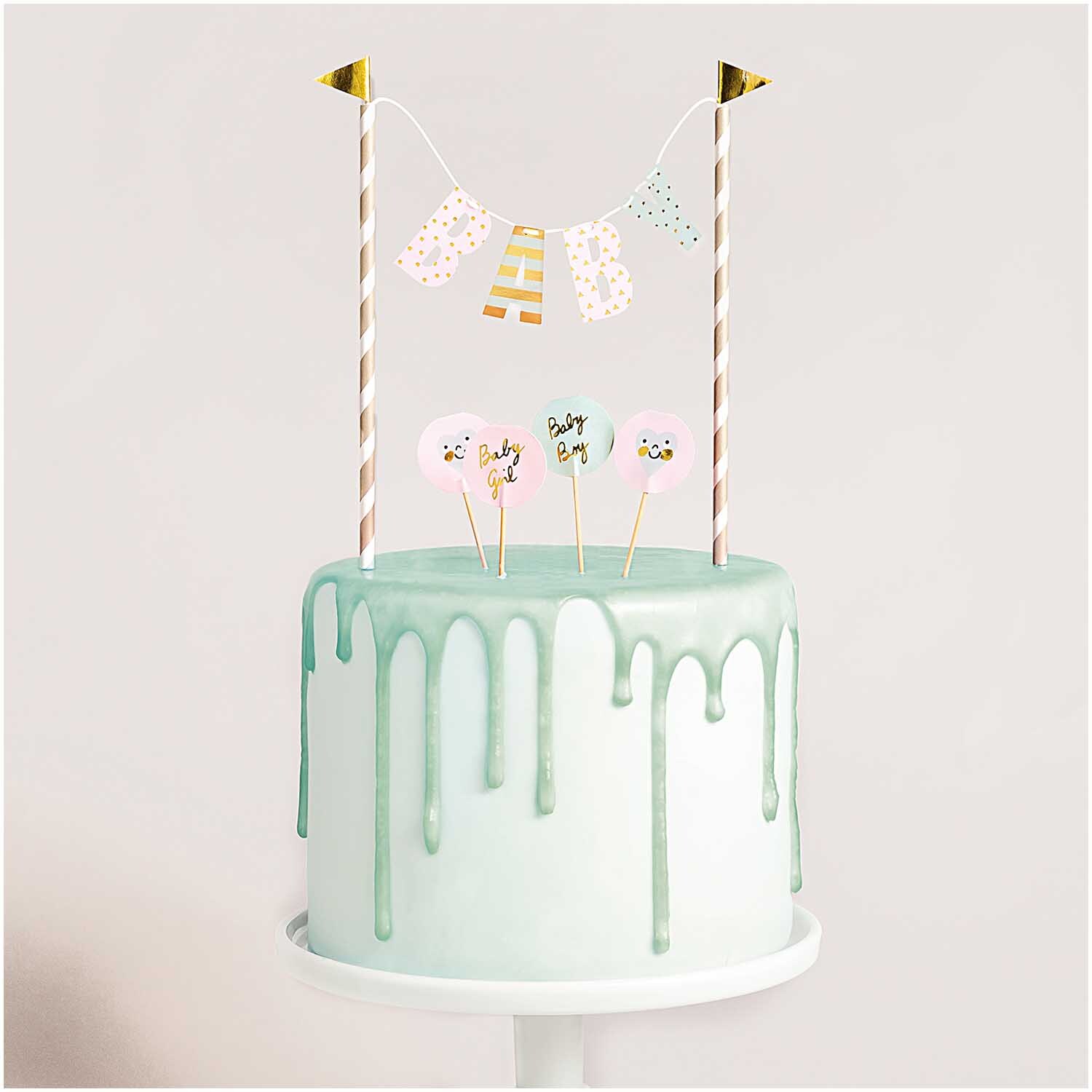 Kuchendekoration Baby: Eine pastellgrüne Torte mit goldenen Wimpeln und niedlichen Baby-Motiven von Rico Design.