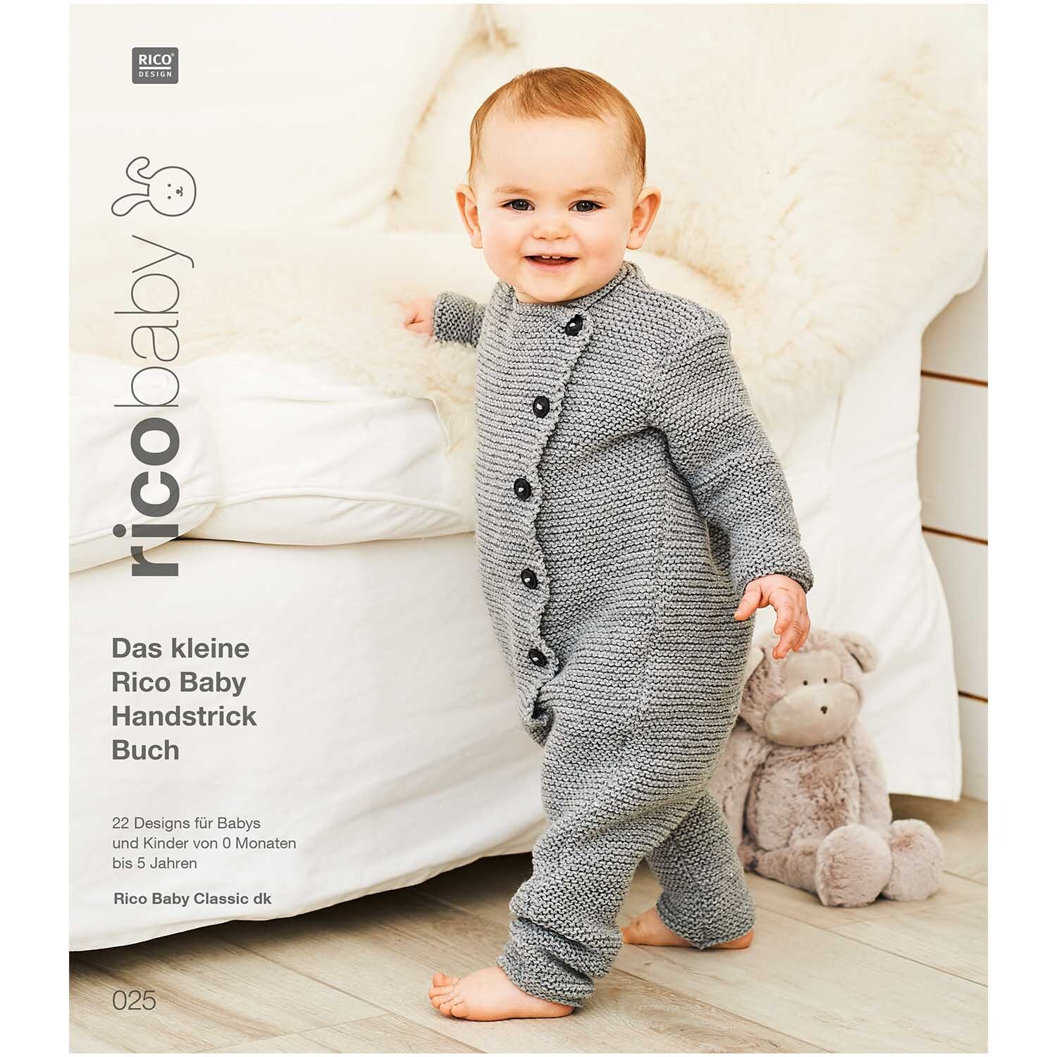 Rico Baby Heft Nr.25 zeigt ein lächelndes Baby in einem grauen Strickanzug von Rico Design neben einem Plüschtier.