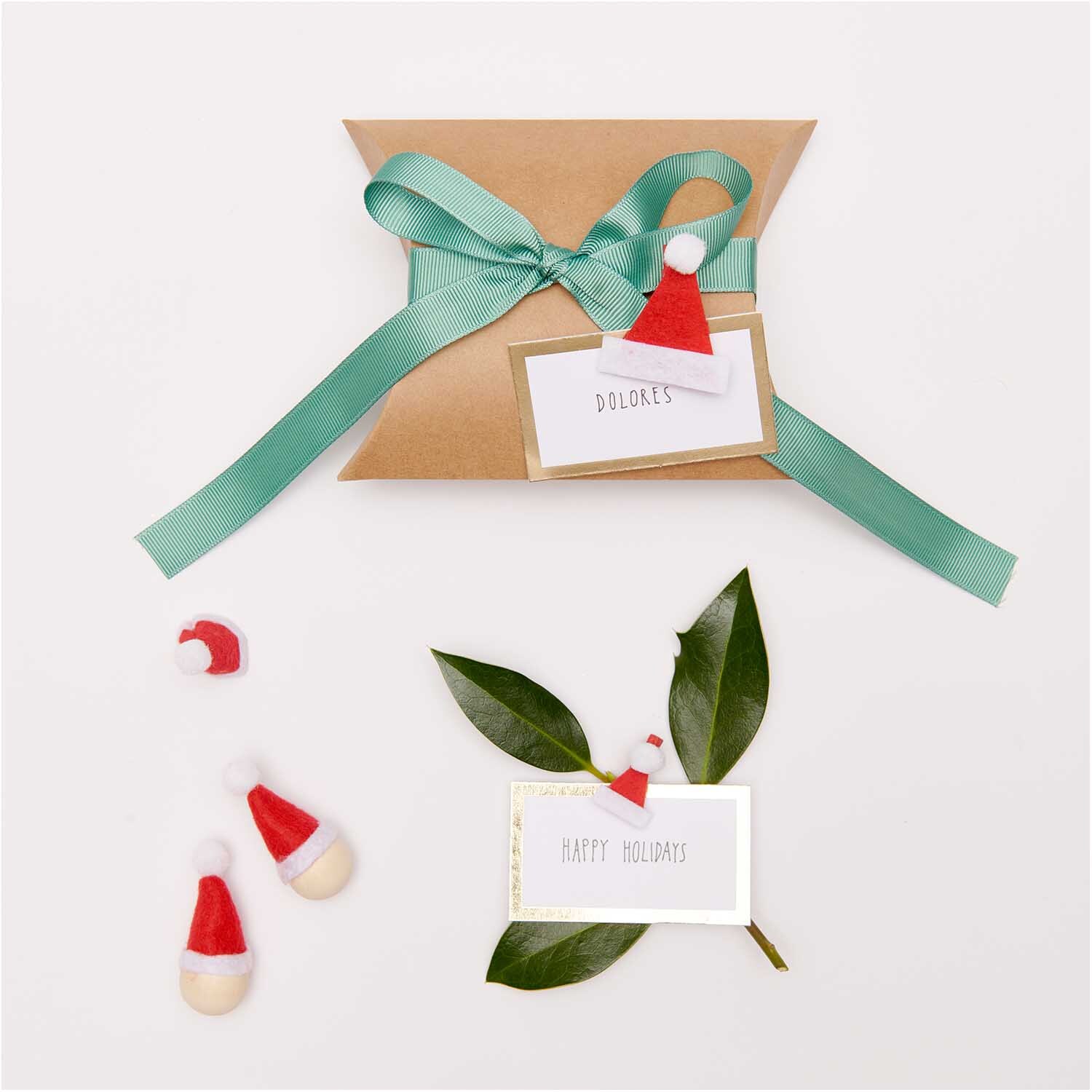 Dekoklammern Weihnachtsmützen von Rico Design auf Geschenkverpackung mit grünem Band und Grußkarten.