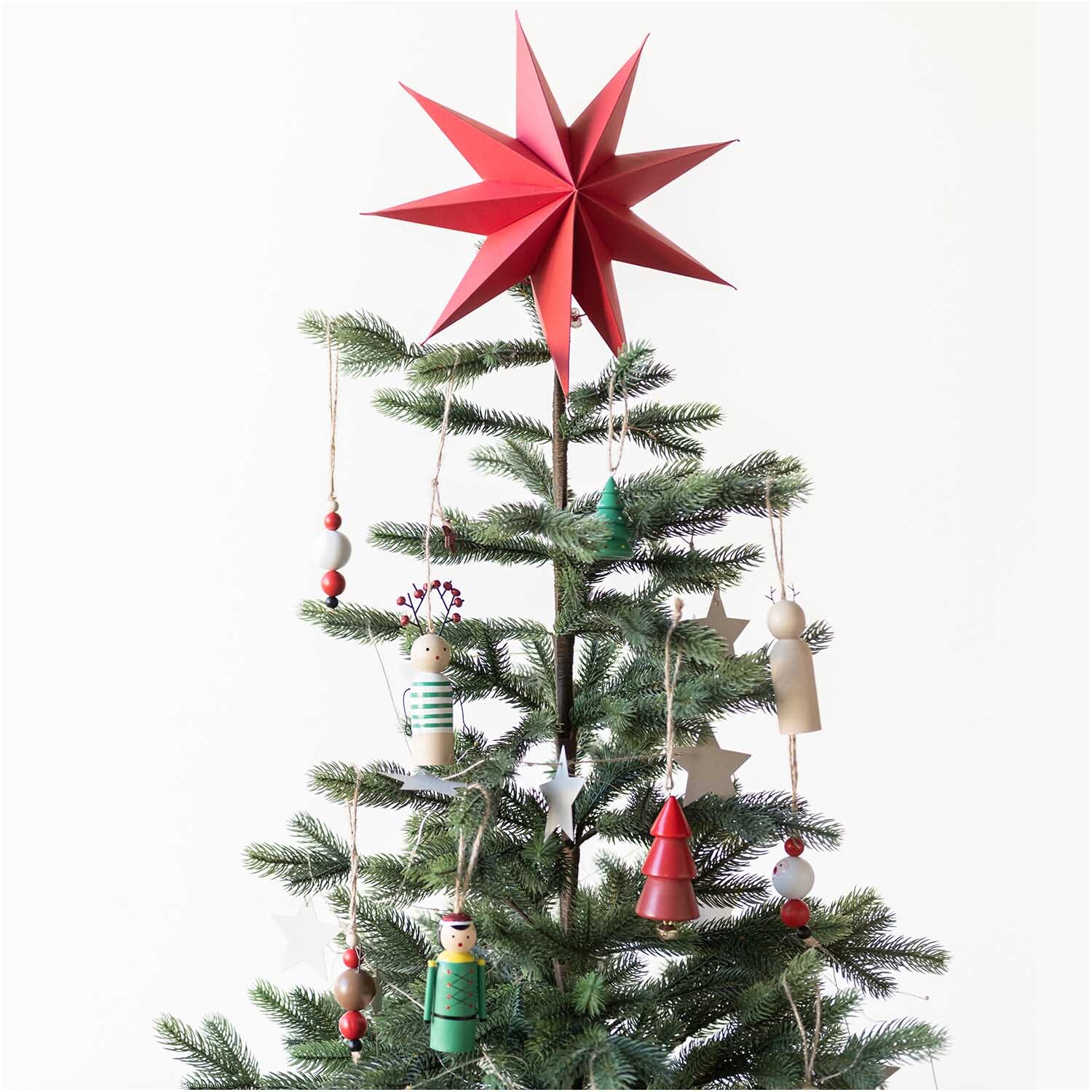 Holzhänger Santa aus Holzkugeln schmückt einen Weihnachtsbaum. Der Anhänger ist rot-weiß und von Rico Design.