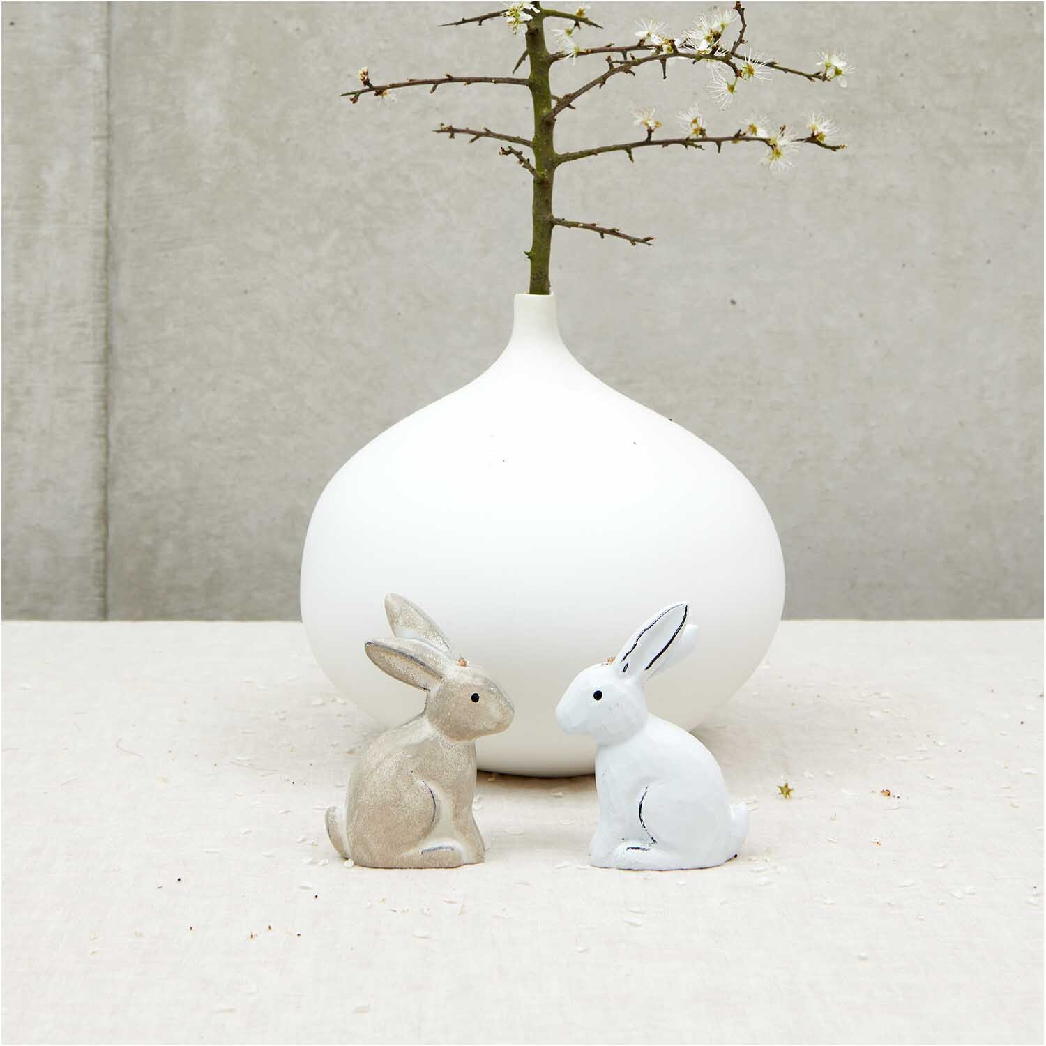 Holzanhänger Hase groß weiß 1 Stück: Zwei Hasenfiguren vor einer weißen Vase mit Zweig.
